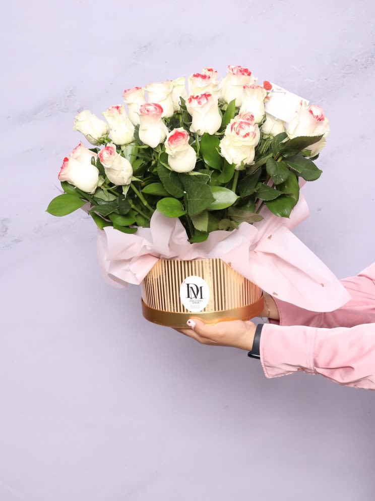 Elizabeth Bloom - Elizabeth Bloom is a timeless and elegant floral arrangement featuring 24 premium white roses with soft pink tips, beautifully designed in a luxurious flower box with delicate blush wrapping.  This arrangement embodies grace, purity, and romantic charm, making it the perfect choice for anniversaries, birthdays, celebrations of love, or refined everyday gifting. Its classic palette and lush rose presentation create a sophisticated statement that never goes out of style.  Each arrangement is handcrafted with care using fresh, high-quality roses. Bloom openness may vary slightly due to natural characteristics, while maintaining the overall design and elegance.