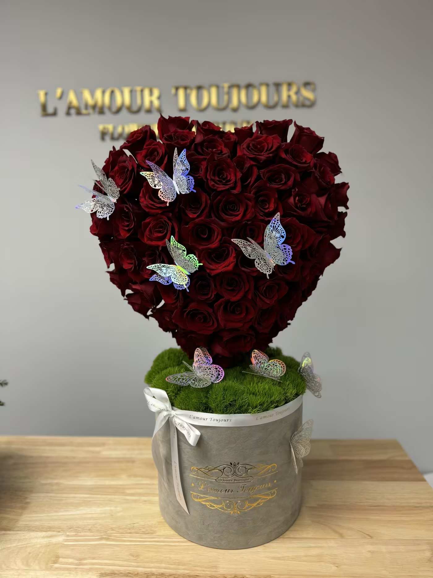 Signature Heart-in-the Box - The ultimate Valentine's Day flower arrangement! The box contains a bed of moss with roses in the shape of a heart atop. The Rose Heart is standing at 1.5 feet tall decorated with 50-60 roses and butterflies
