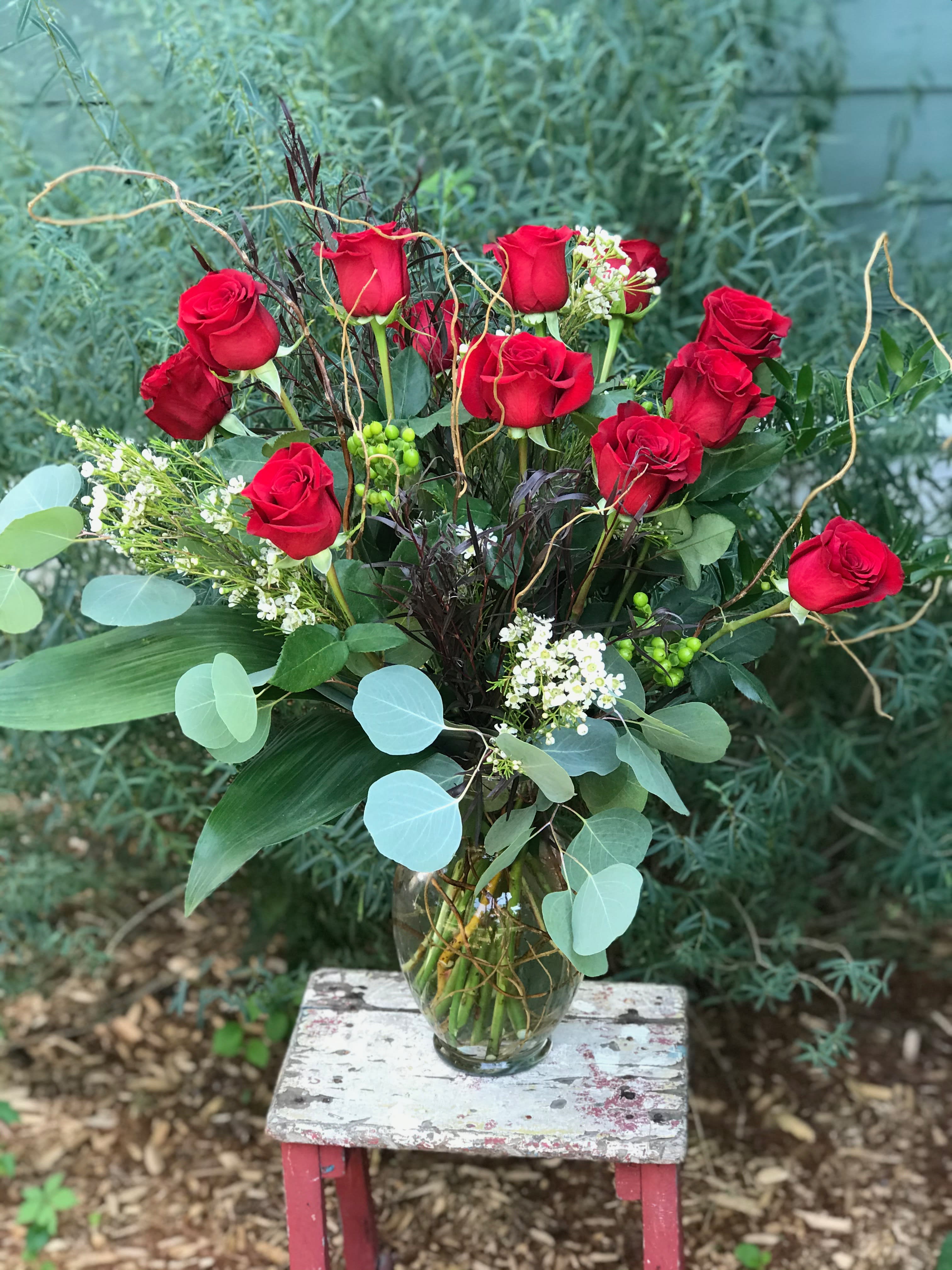The Dozen - Premium red roses arranged artfully with branches, assorted foliage and unique filler. Simply perfect and not your average rose bouquet!