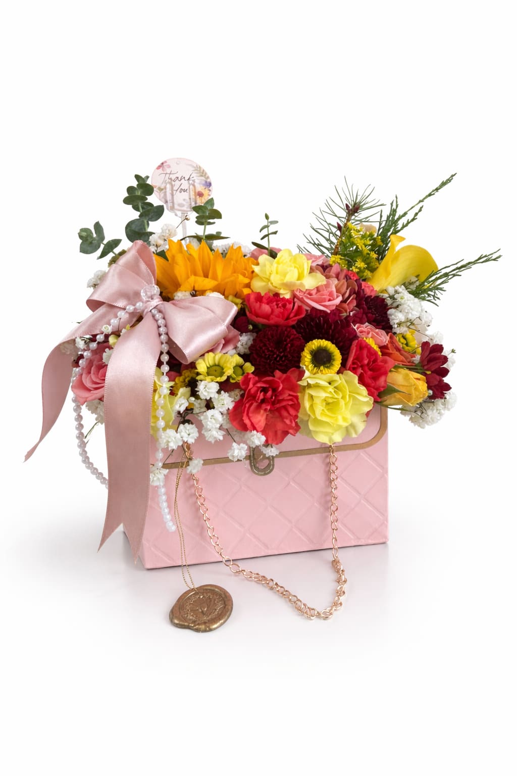 Vera - This charming floral arrangement features warm golden yellow blooms, soft blush flowers, and rich berry tones for a cozy, romantic feel. Designed in a blush pink quilted keepsake box and finished with a satin bow, pearl accents, and a gold chain detail, it’s perfect for birthdays, thank-you gifts, sympathy and condolences, thinking-of-you moments, or everyday happiness. Available for local flower delivery in Carlsbad and surrounding areas.