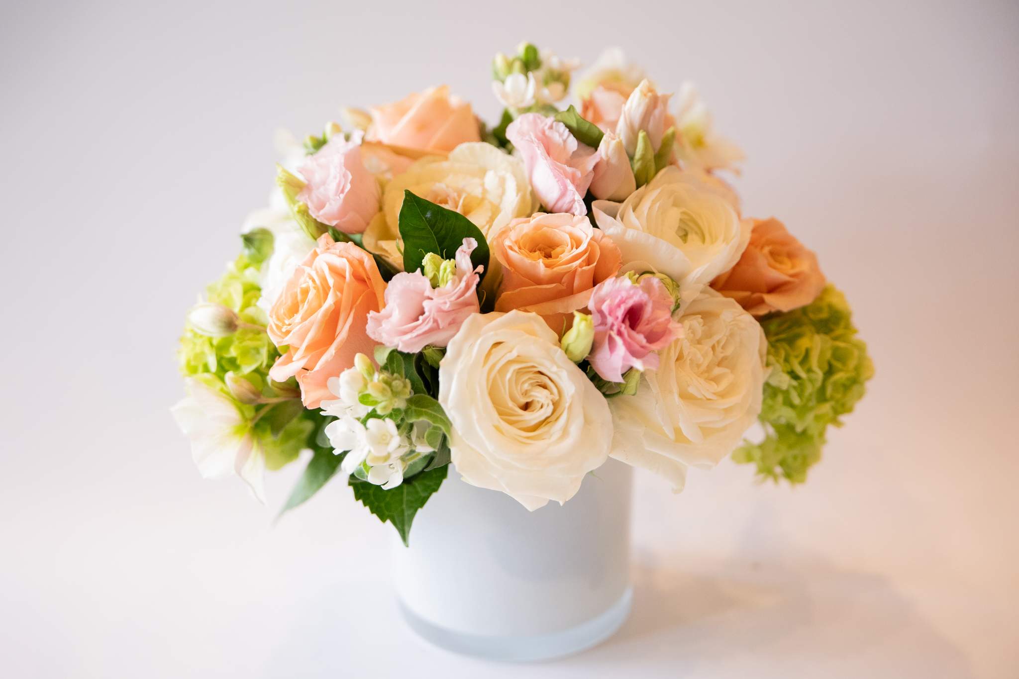 Blush  - Blush is a floral composition made with fresh seasonal blooms that reflects the colors and feelings of the upcoming season. Delicate pink, peach, white, and cream tone blooms in a glass vase