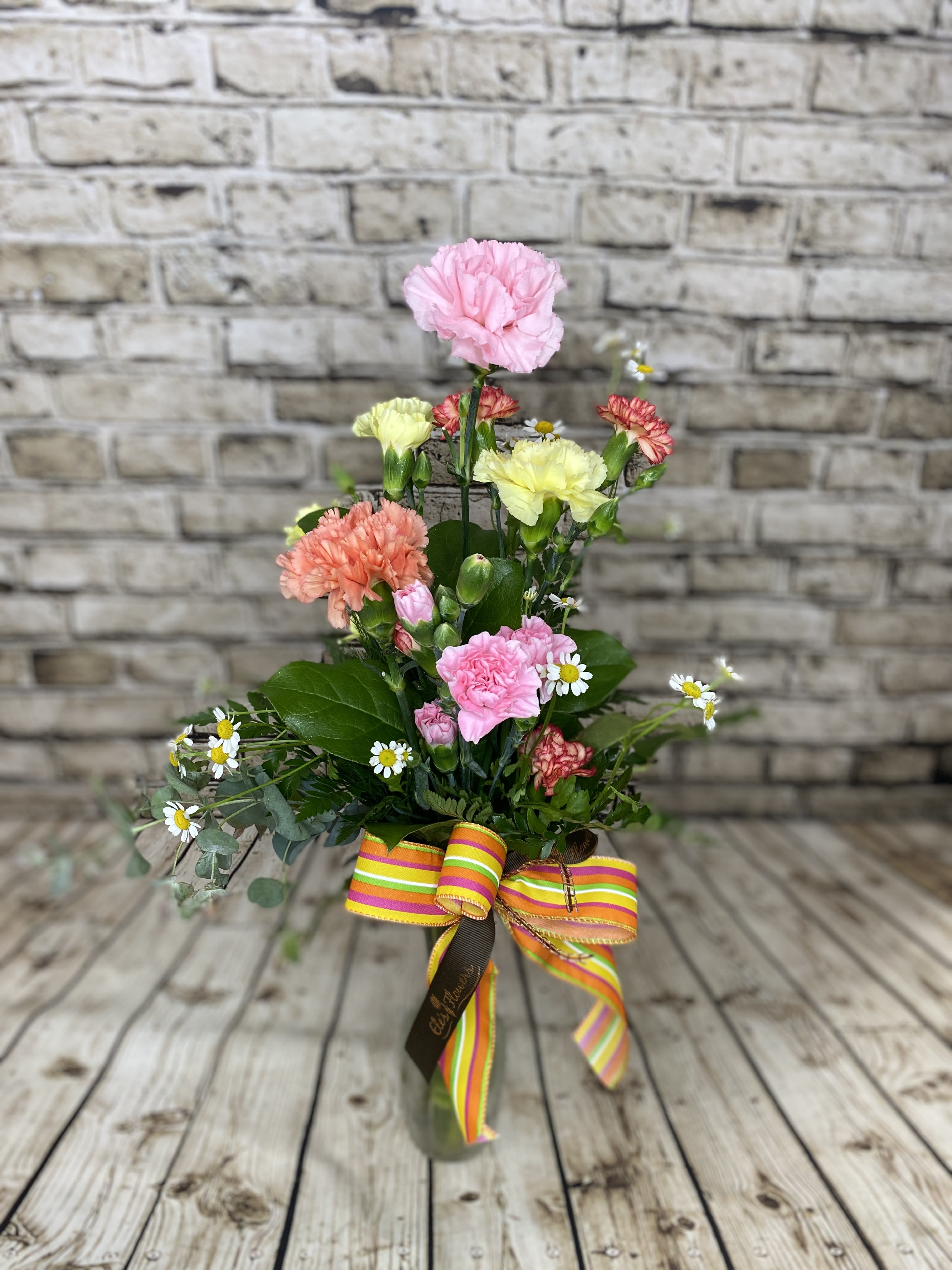 Petite Carnation - Looking for something simple and good for a small area? Look no further! Our cute Petite Carnation arrangements include colorful stems of large and mini carnations with accent flowers and greens. It's a wonderful option for small spaces or wanting to say, "Hi."  Photos are representations of what we are able to create. Have any special requests? Add those in the "special instructions" section of your order!  Approximate Dimensions: 14"H x 8"W