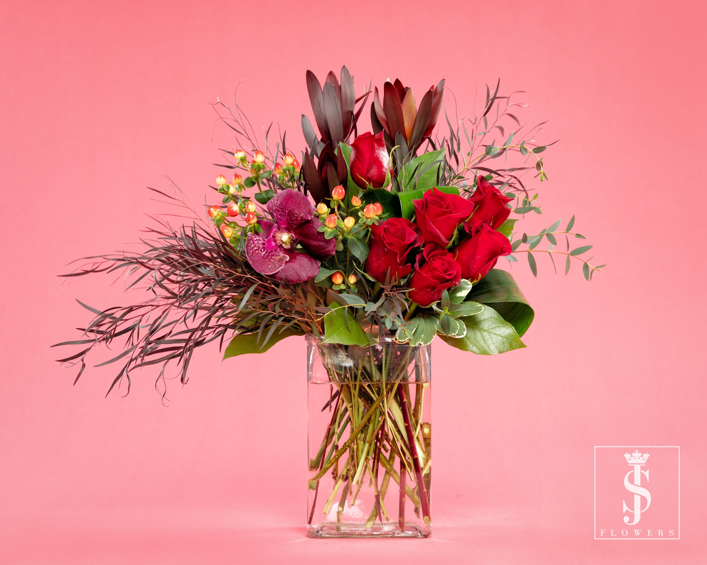 Ruby Love  - This enchanting arrangement features 6 meticulously selected red roses, and vanda orchids exuding elegance and grace. The striking contrast of these vibrant blooms evokes a sense of unity, reminding us of the strength that lies in diversity. With each petal unfurling like a brushstroke, the roses embody the essence of love and courage.