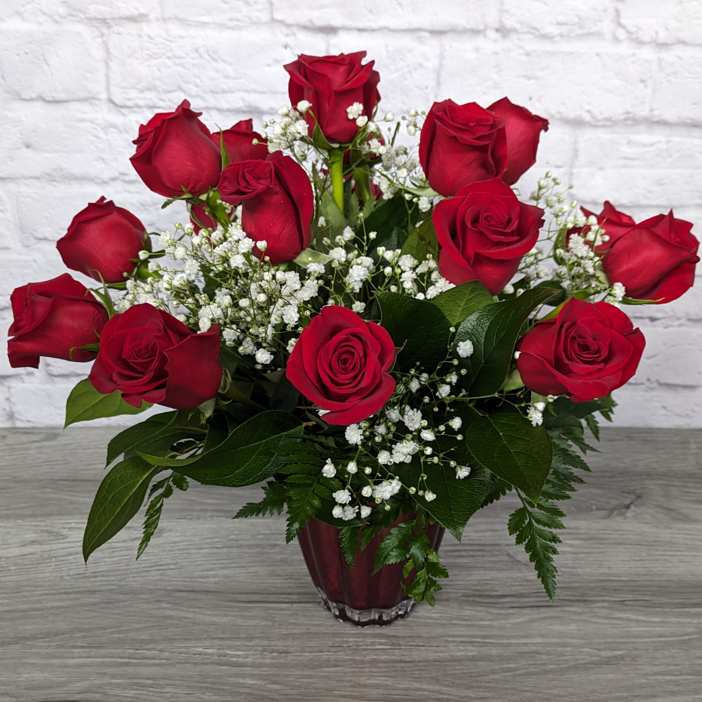 Refined Red Roses - Refined Red Roses uses shorter rose stems in a colored glass vase to create a stunning and more compact version of a long stem rose bouquet.  All Round Orientation 16.5"H X 18"W  