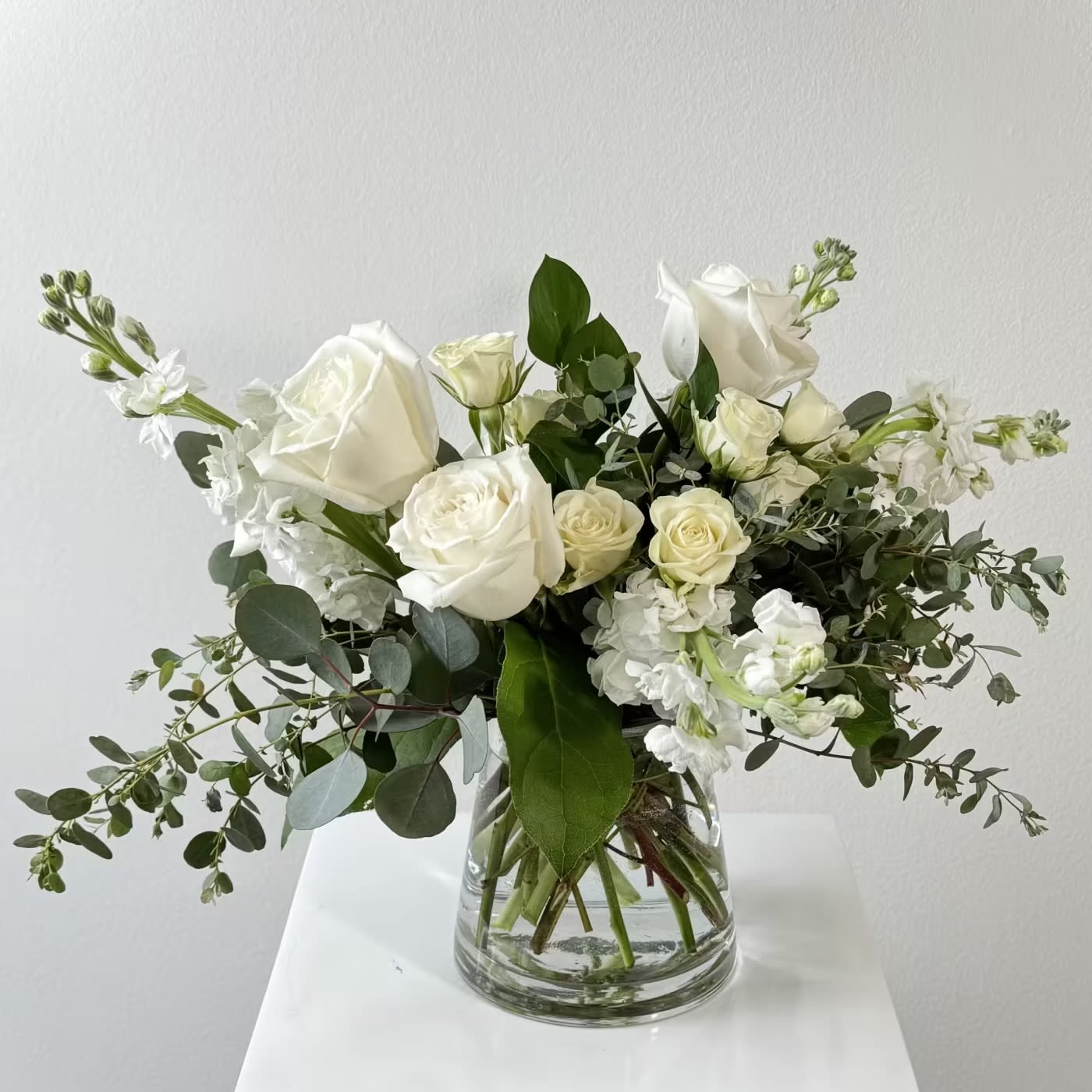 Fresh Linen Bouquet - Fresh Linen Bouquet – Crisp White Rose &amp; Stock Bouquet with Eucalyptus Breathe in serenity with Fresh Linen, a pristine arrangement that captures the clean, airy essence of sun-dried sheets. Fragrant white stock releases a subtle spicy-sweet scent, mingling with classic white roses, delicate white spray roses, and cooling eucalyptus branches. Presented in a minimalist clear glass vase, this all-white design radiates purity, calm, and understated luxury—perfect for creating tranquil moments.  What Makes Fresh Linen Irresistible: White Stock: Tall, clustered blooms deliver intoxicating fragrance and soft texture. White Roses: Timeless icons of innocence, loyalty, and new beginnings. White Spray Roses: Petite, multi-bloom stems add playful volume and grace. Eucalyptus: Silver-green leaves provide aromatic freshness and modern contrast.  Expertly arranged and delivered in a glass vase for instant display. Ideal for sympathy tributes, wedding décor, new baby celebrations, housewarmings, get well wishes, or spa-like home ambiance. Fresh linen flowers, white stock rose bouquet, eucalyptus white spray roses, all white floral arrangement, fragrant sympathy flowers, clean white wedding bouquet, new baby white roses, housewarming fresh flowers, same-day minimalist bouquet delivery, eucalyptus scented floral gift. Transform any room into a peaceful retreat and order Fresh Linen now. Fresh Linen Bouquet, white roses, eucalyptus floral, sympathy flowers, clean elegance.