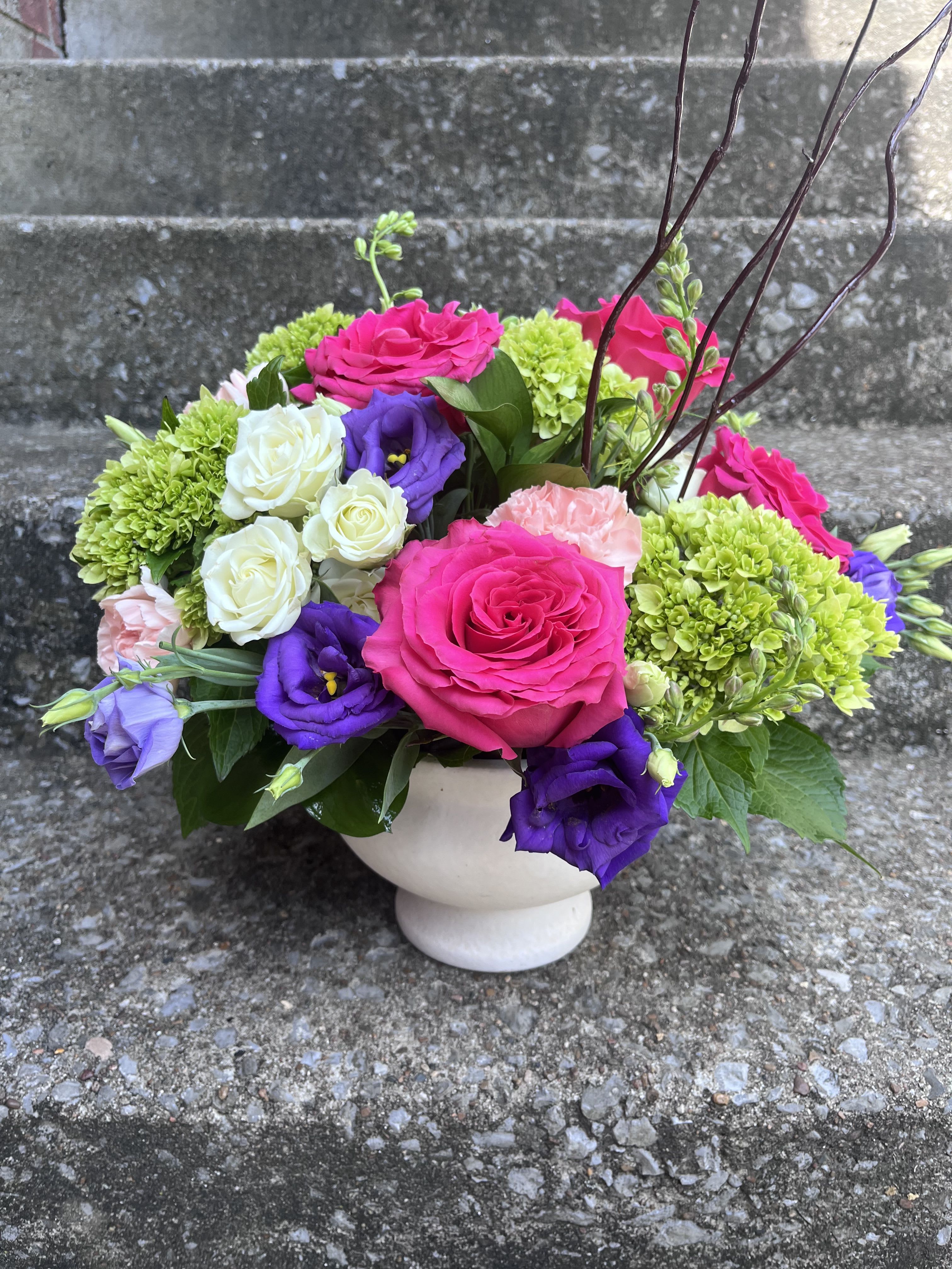 Sweet Gardens  - This arrangement has green hydrangea’s, hot pink roses and purple lisianthus, white pray roses, light pinks carns, Curley willow with beautiful greenery. 