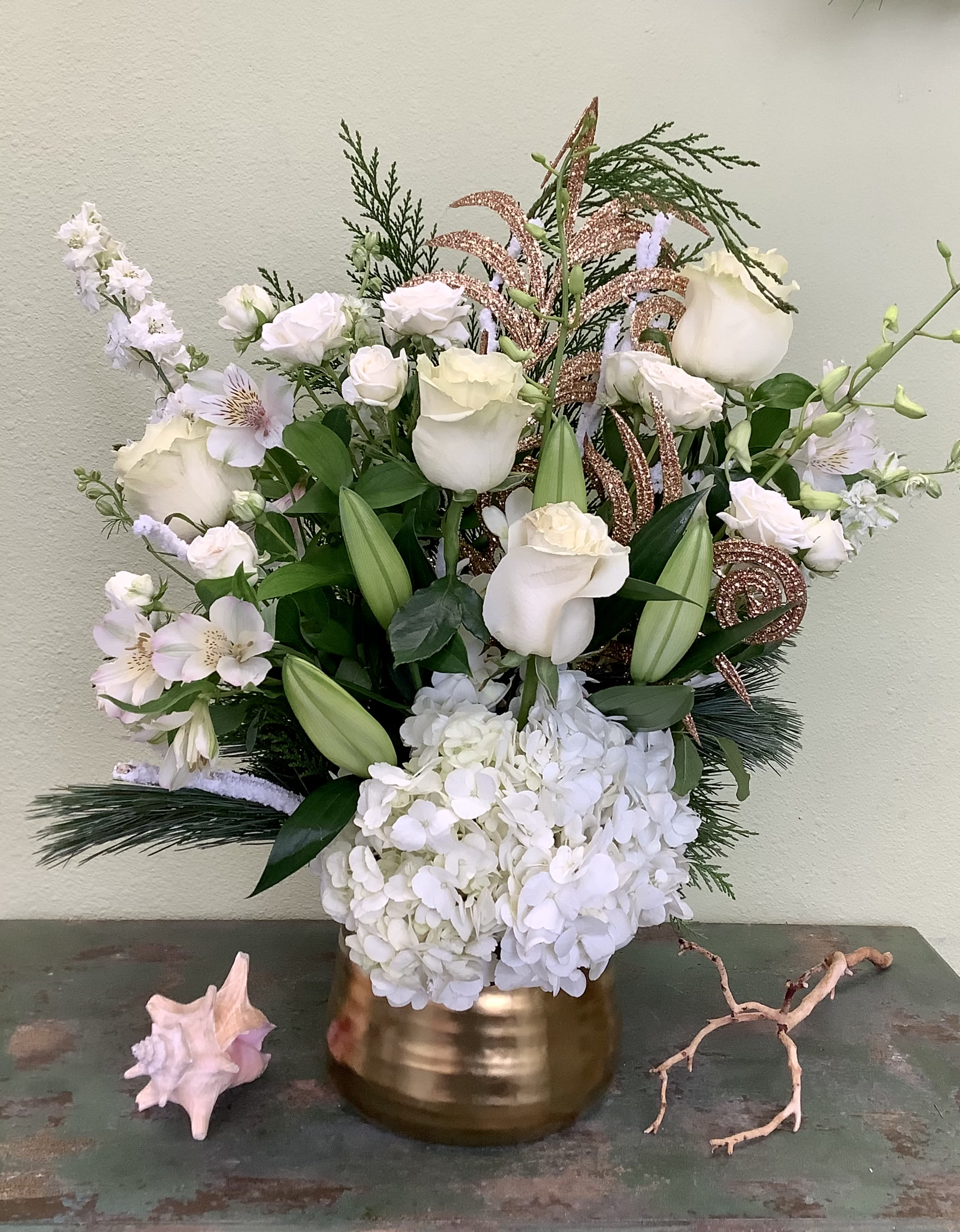 Joy to the World - This showstopper will bring beauty and joy to your Christmas and New Year!  Artfully designed in a brilliant gold vase and featuring a variety of premium winter white blooms and holiday greens.  Flowers  and container may vary, please call if this is a concern. 