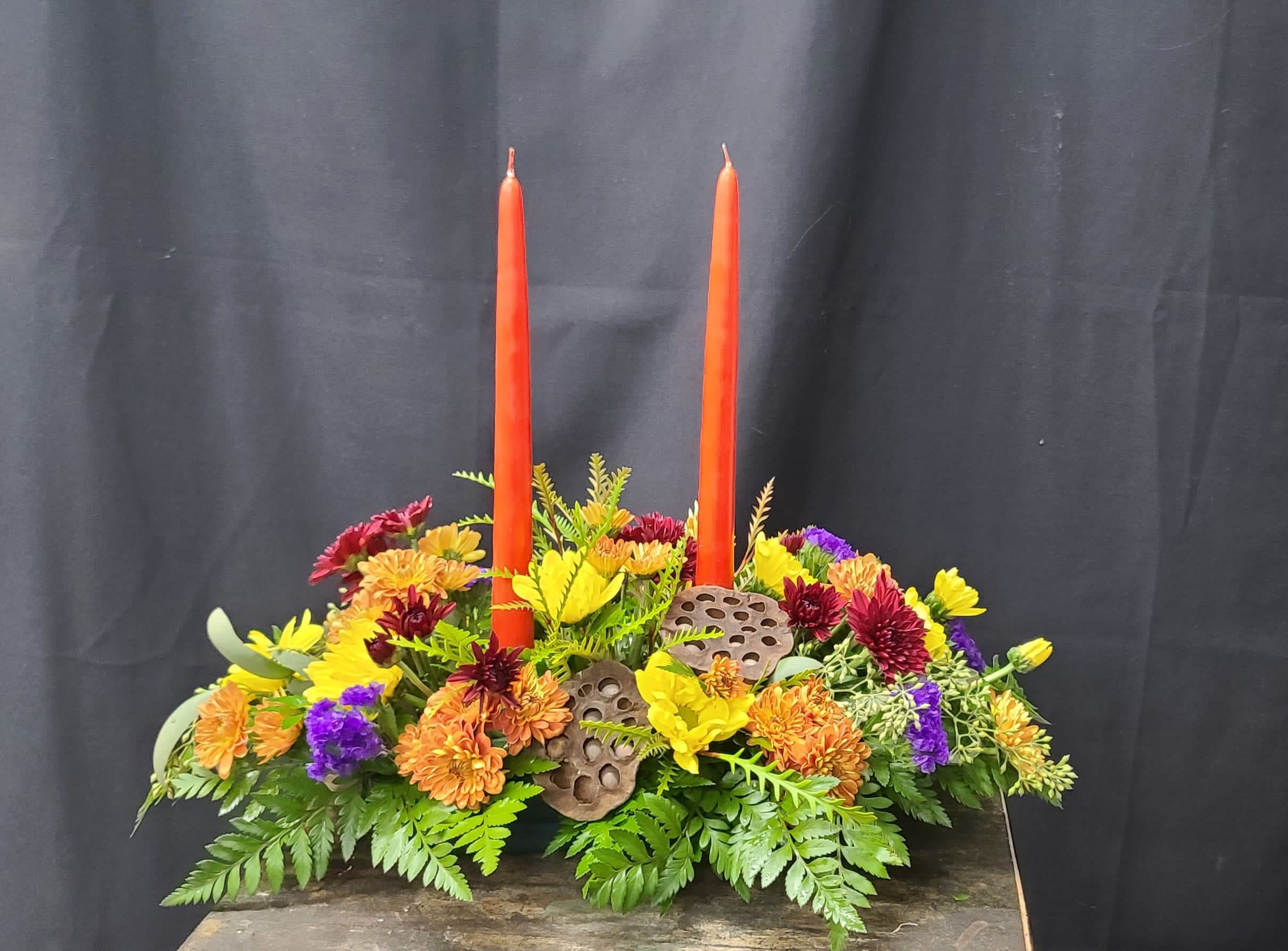 Designers Choice Thanksgiving Centerpiece with candles - Fall colored centerpiece with natural accents and twin bittersweet colored candles. Fall mums in a variety of colors and textures really make this centerpiece glow. Our designers use the best available flowers and foliage to make a one of a kind centerpiece for you. 