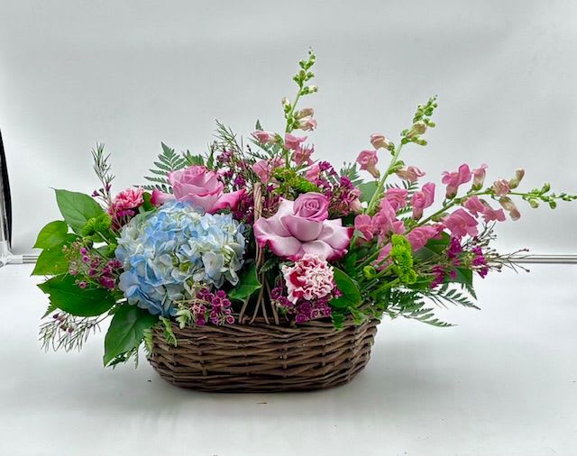 The Josephine Basket - Named after my grandmother, who loved simple, beautiful flowers.  A beautiful wicker basket, with greens, lavender roses, hydrangea, carnations, snapdragon, button mums, and wax flower. A timeless arrangement perfect for everyday, birthdays, thank you and sympathy  