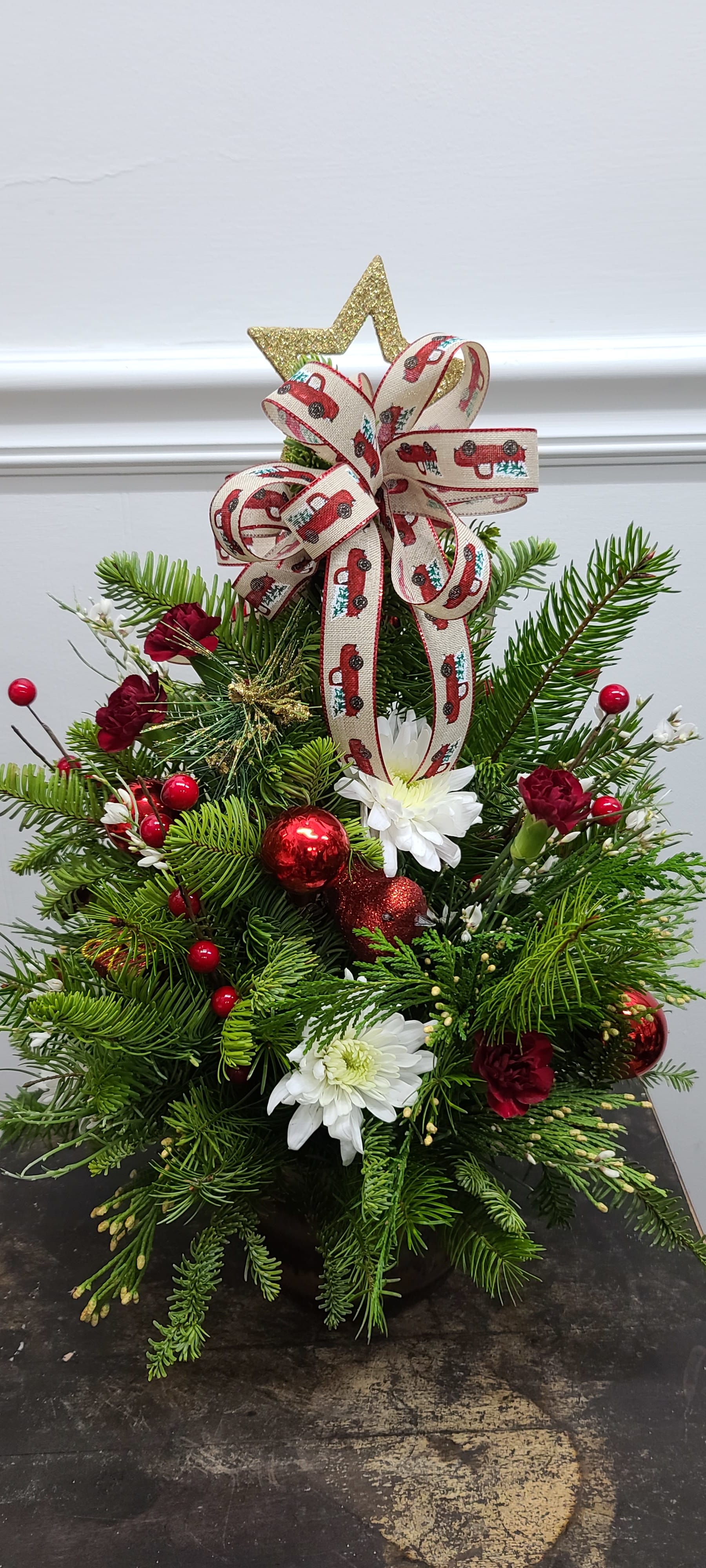 Designers choice Christmas Tree - An endearing fresh pine Christmas tree made from a mix of fresh cut spruce, frasier, and cedar brings the smell of Christmas inside, decorated with red glass balls and festive accents and topped with our favorite red truck Christmas ribbon. Sure to bring smiles and joy to anyone. 
