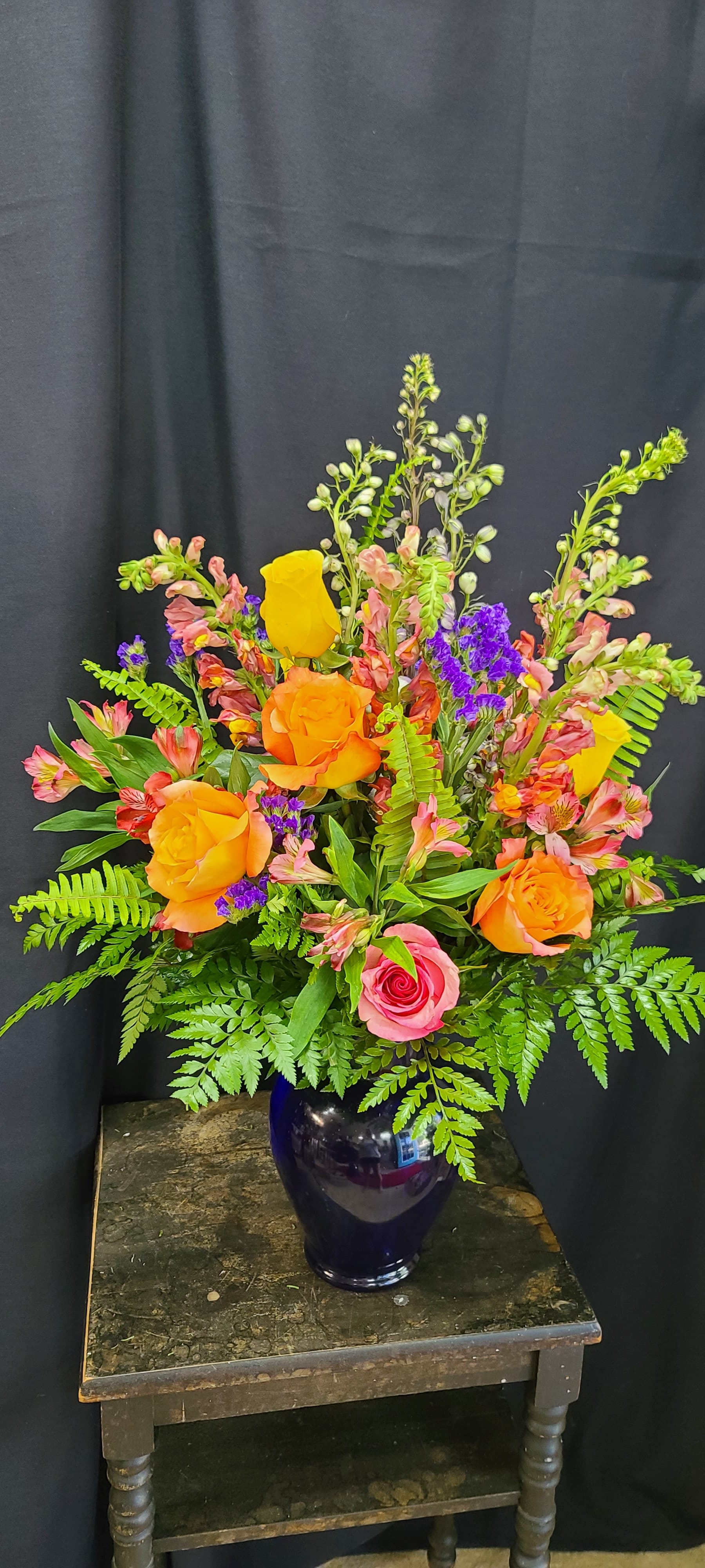 Fall Magic - Fall jewel tones in our favorite cobalt blue vase. The seasons best roses, snap dragons, statice, alstromaria, &amp; crisp green ferns. This stunning arrangement makes a statement at the funeral home, for birthdays, at the office, at church, or just to let someone know you love and miss them 