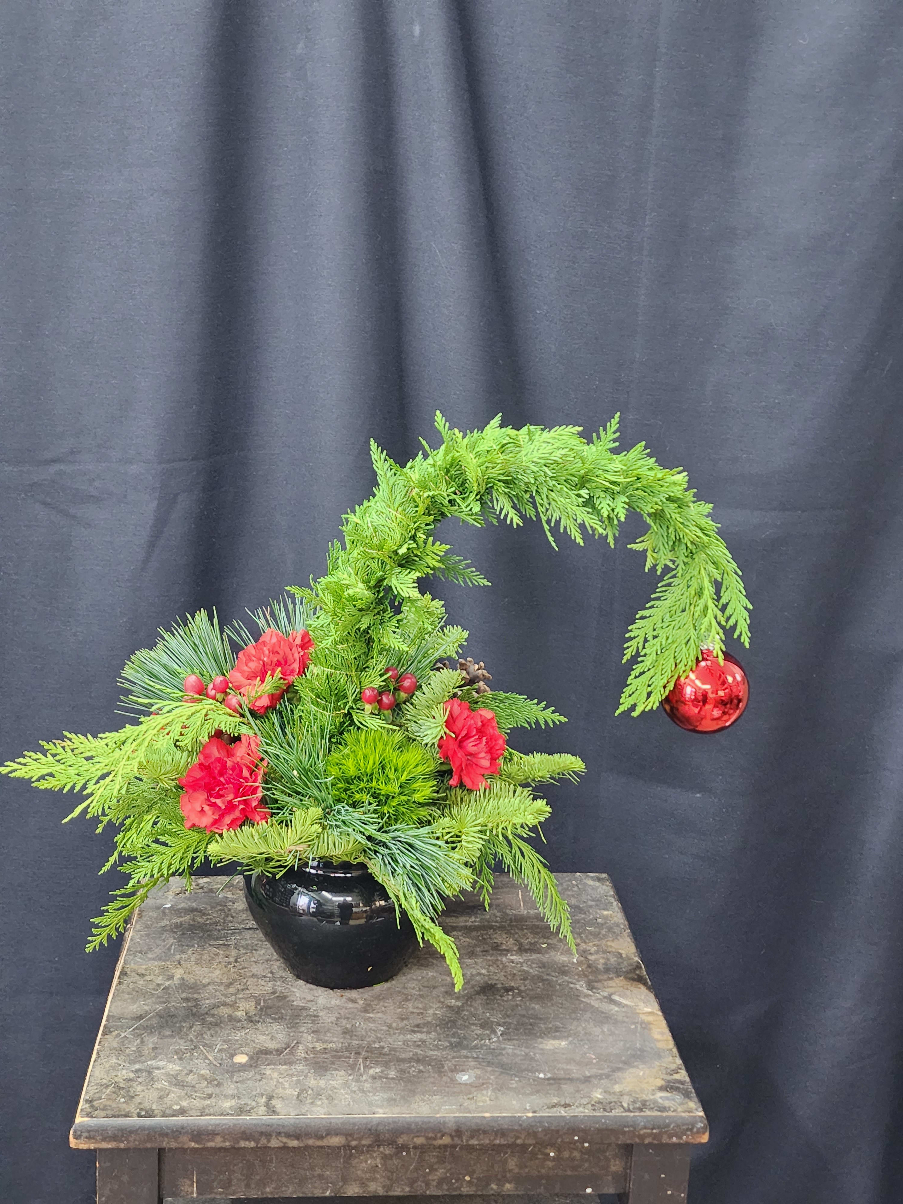 Feeling Grinchy - Our wonderfully whimsical grinch tree. Trimmed with red carnations, berries, and pine cones. The perfect way to make them smile and reminisce.