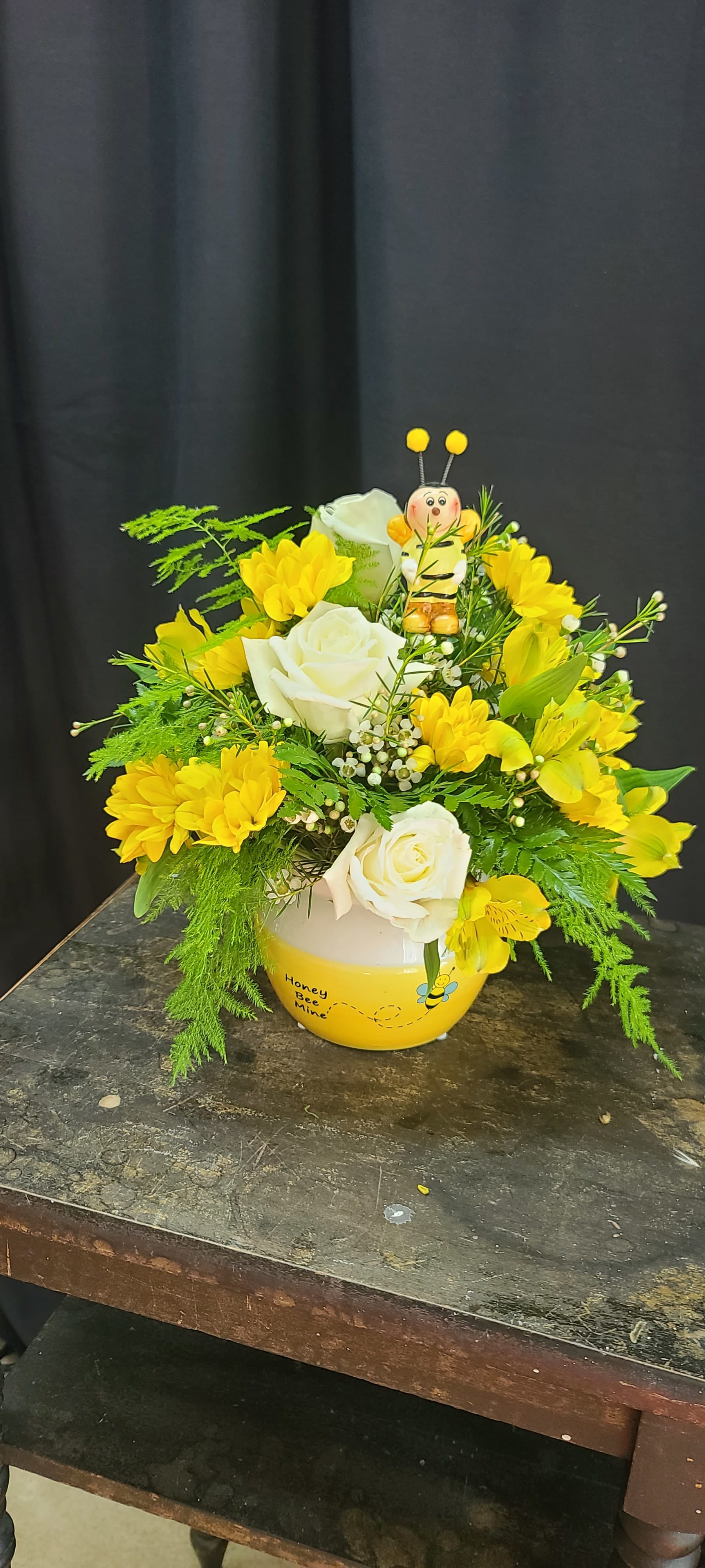Honey Bee Lover - This super cute honey bee ceramic pot is filled with bright sunny alstromaria, yellow daisies, white roses and wax flower. Topped with Buzz the honey bee. 