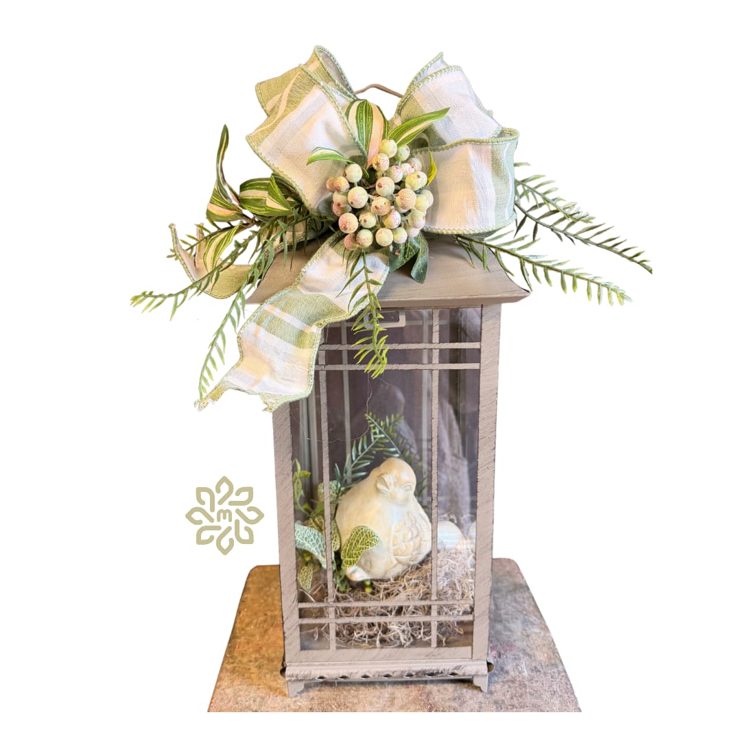 Whispering Garden Bird Lantern - Bring a touch of timeless charm to your home with our Whispering Garden Bird Lantern with Complimentary Bow. This decorative lantern features a delicately crafted bird figurine nestled inside, creating a peaceful, nature‑inspired focal point for any room.  Perfect for mantels, entryways or as a sympathy gift. Each lantern is finished with a complimentary coordinating bow for an elegant, ready‑to‑display look.