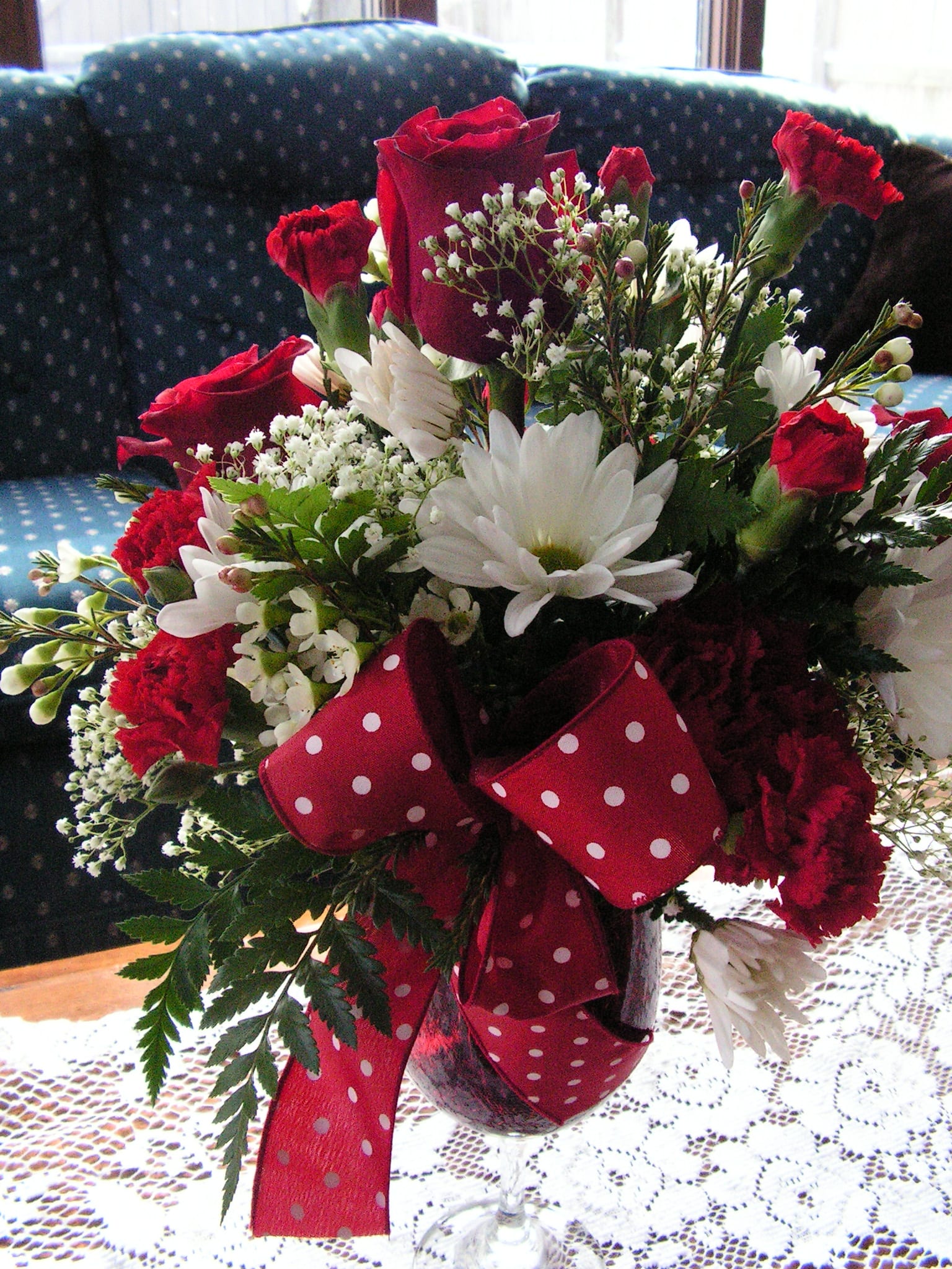 La Vin Rose - Red Roses, Red Mini Carnations, White Daisies, and babies breath fill this fun Wine Glass arrangement.