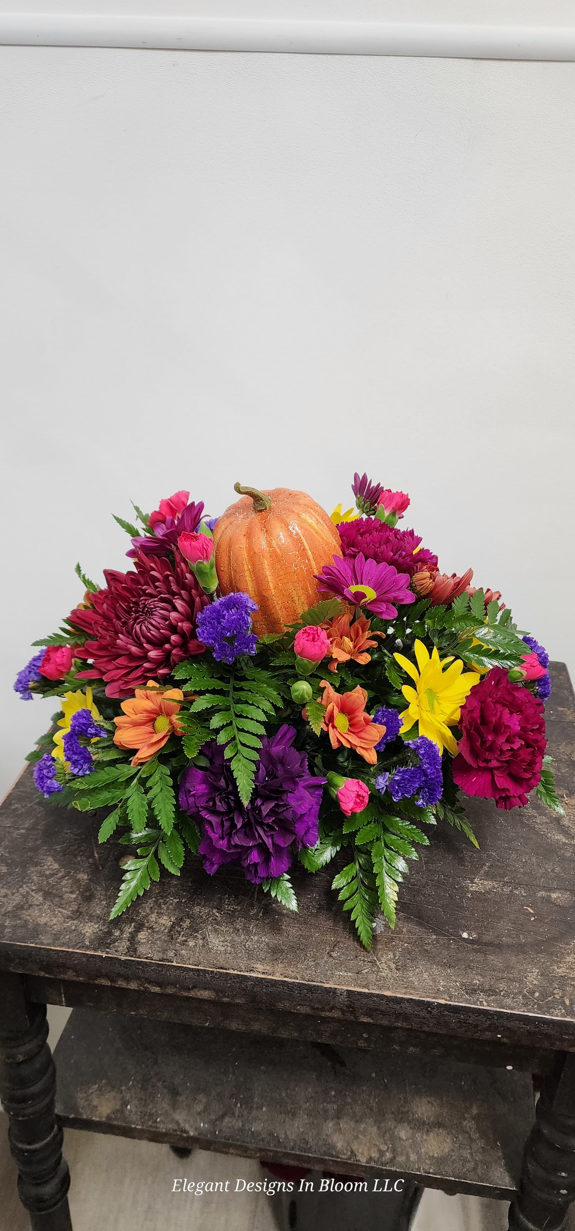 Low Autumn Designers Choice  - Our designers will create a beautiful fall display to enhance your Thanksgiving table. Flowers may include chrysanthemums, Carnations, lilies, roses, berries, accent flowers, and mixed greens.