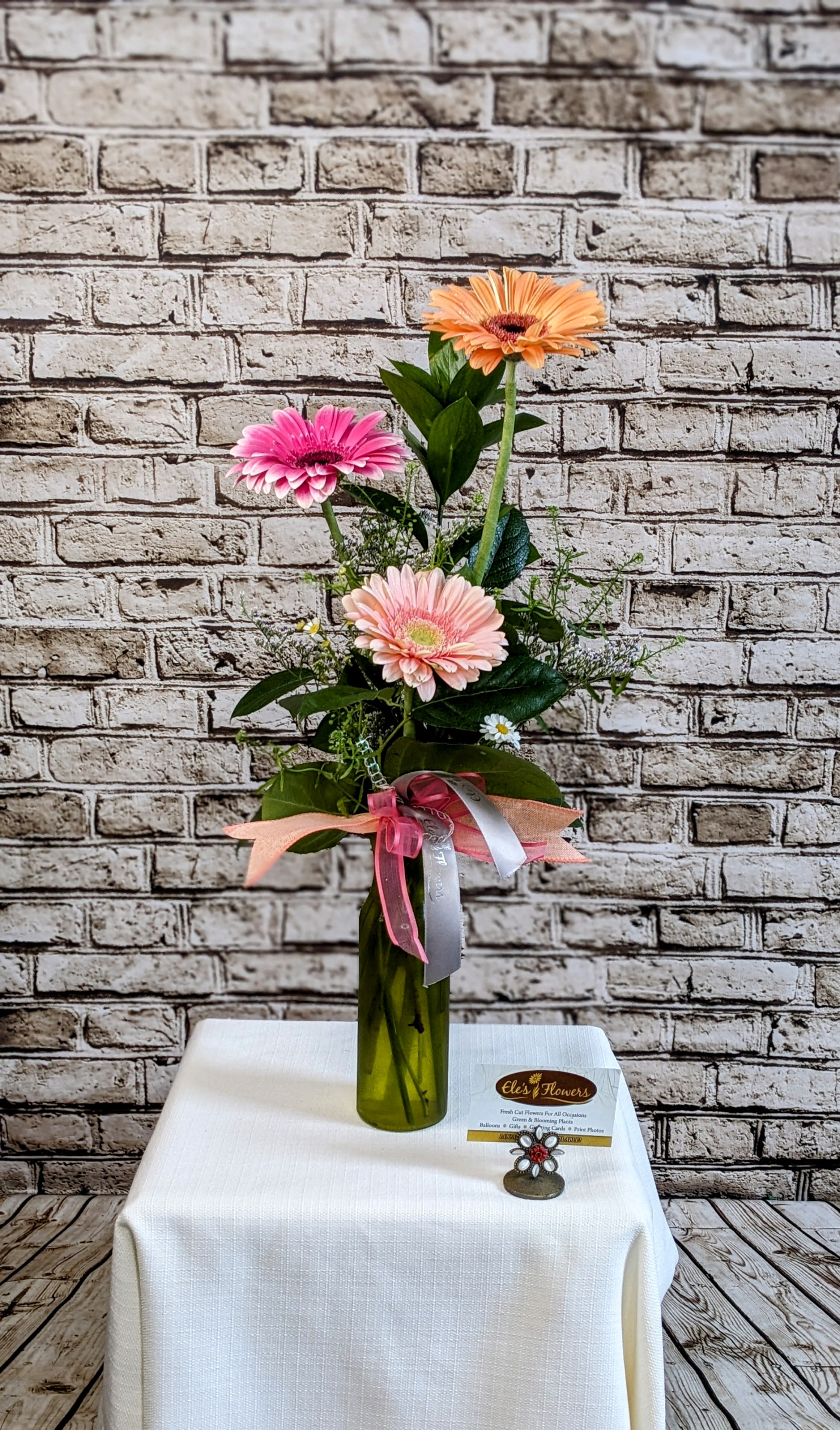 Gerbera Daisy Trifecta  - A fun assortment of the ever so popular Gerbera Daisy! This is a great way to send Birthday wishes, Get well wishes and so much more. Three different colored Gerbera Daisies are arranged in a fun vase situated amongst greenery and accent flowers. Actual colors of daisies may vary from picture based on what is available.   Perfect for small spaces. Approximate Dimensions 17"H x 6"W