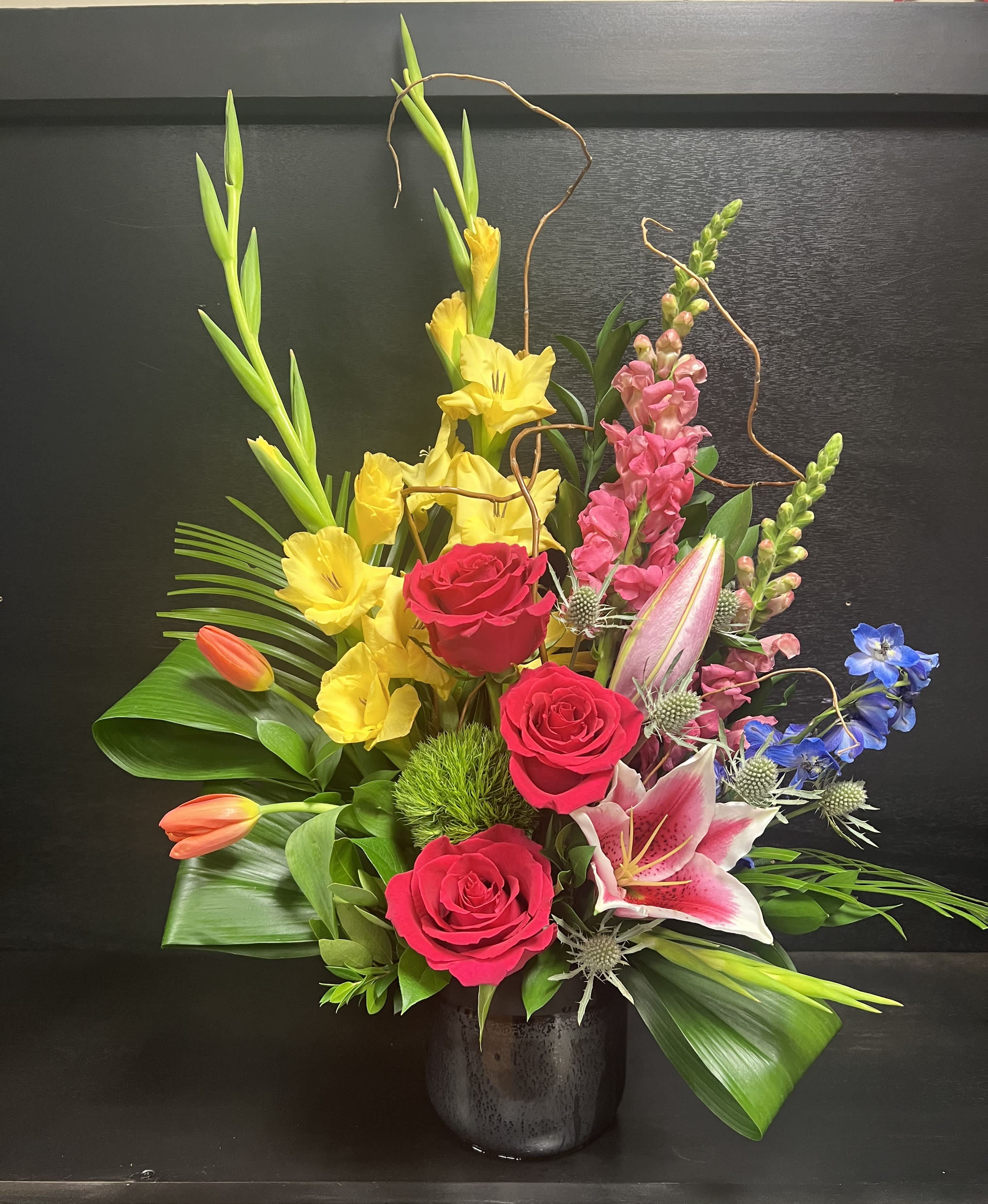Designers Choice Highstyle - Each high-style arrangement is made special and unique. Featuring a mix of roses, lilies, tulips greens, and filler in a ceramic pot. Please be advised, that the flowers and containers may vary depending on store availability. 