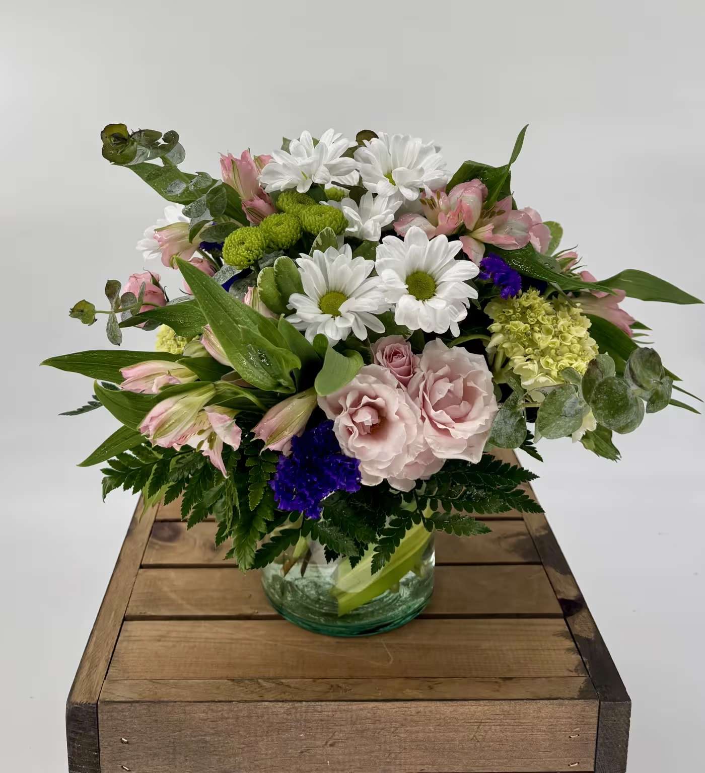 Fluttering Light (BB) - Our charming Fluttering Light flower arrangement, filled with green hydrangea, pink spray roses, white daisies, purple Statice, pink carnations, and pink alstroemeria, will leave you enchanted with its simple beauty. This delightful arrangement captures the essence of springtime, radiating a sense of cheerfulness, joy, and optimism.