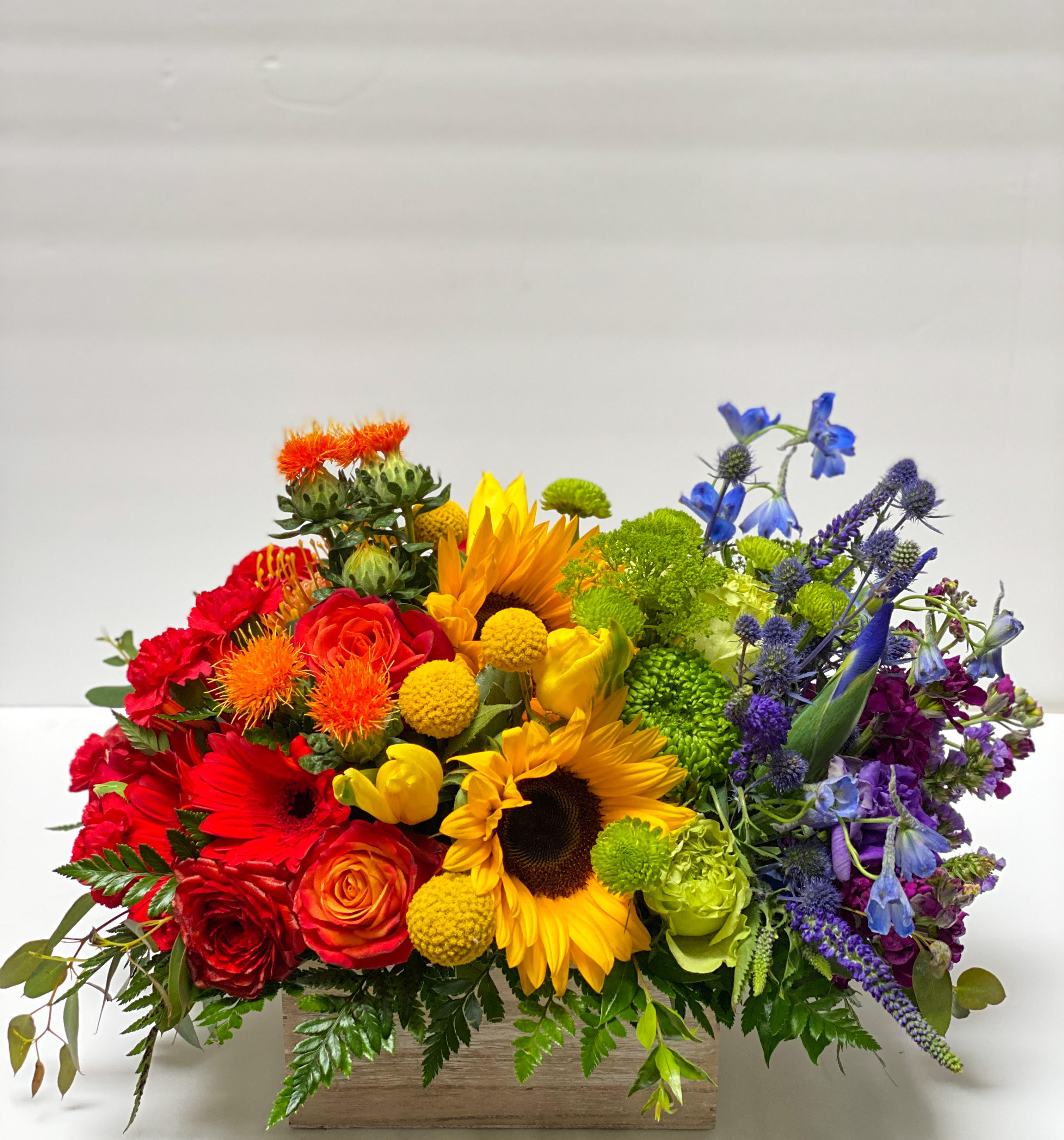 Rainbow Bright - Select this stunning rainbow of flowers in a wooden box. Flowers include roses, sunflowers, iris, and so much more! 