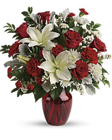 Visions of Love - A vision of love! This luxe bouquet of fragrant white lilies and radiant red roses, hand-delivered in a ruby vase, is the perfect expression of your feelings. This beloved bouquet includes red roses, white asiatic lilies, red carnations, red miniature carnations, white cushion spray roses, white sinuata statice, dusty miller, huckleberry, and lemon leaf. Delivered in a ruby rose vase.
