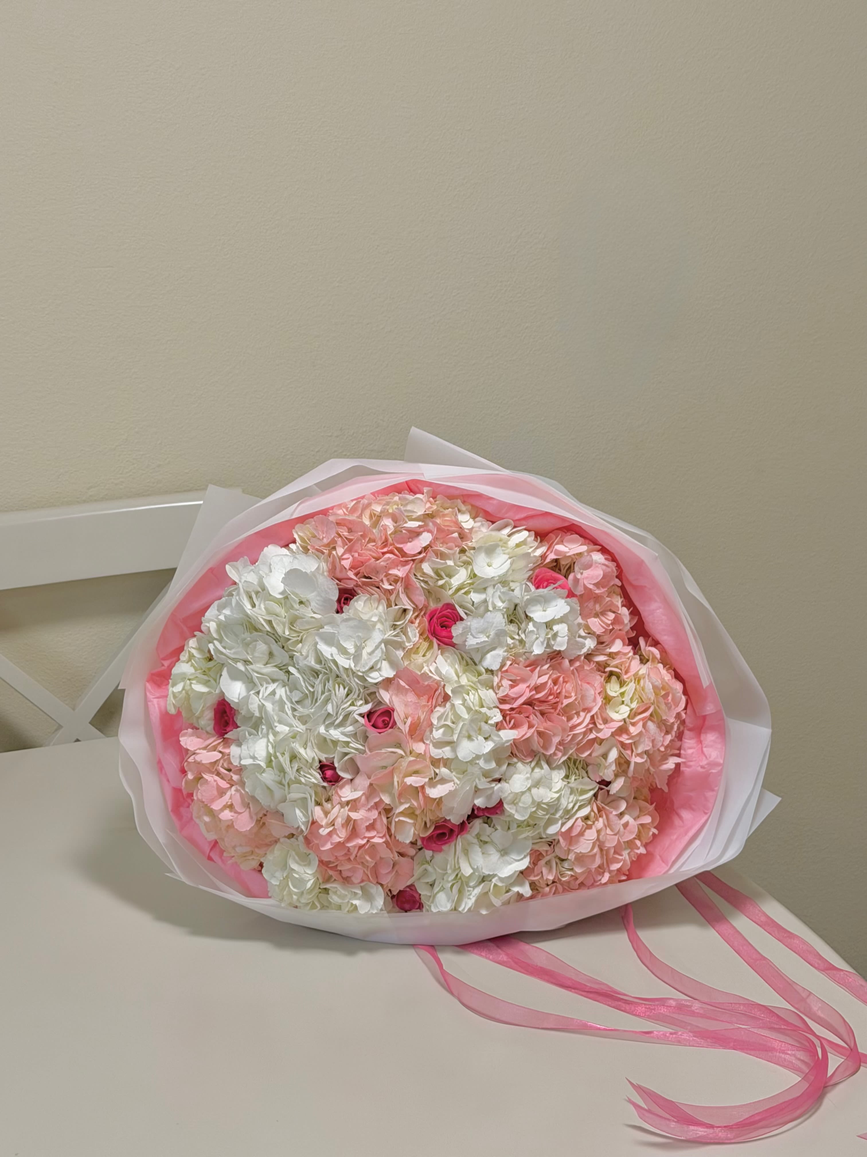 Blushing cloud luxury bouquet - Introducing the Blushing Cloud Luxury Bouquet, a breathtaking blend of soft elegance and romantic charm. This exquisite arrangement features lush white and blush-pink blooms delicately accented with touches of deeper pink, creating a dreamy, cloud-like composition. Wrapped in layered soft pink and white paper with flowing ribbon details, it exudes sophistication and warmth. A stunning statement piece that speaks love, appreciation, and tenderness.