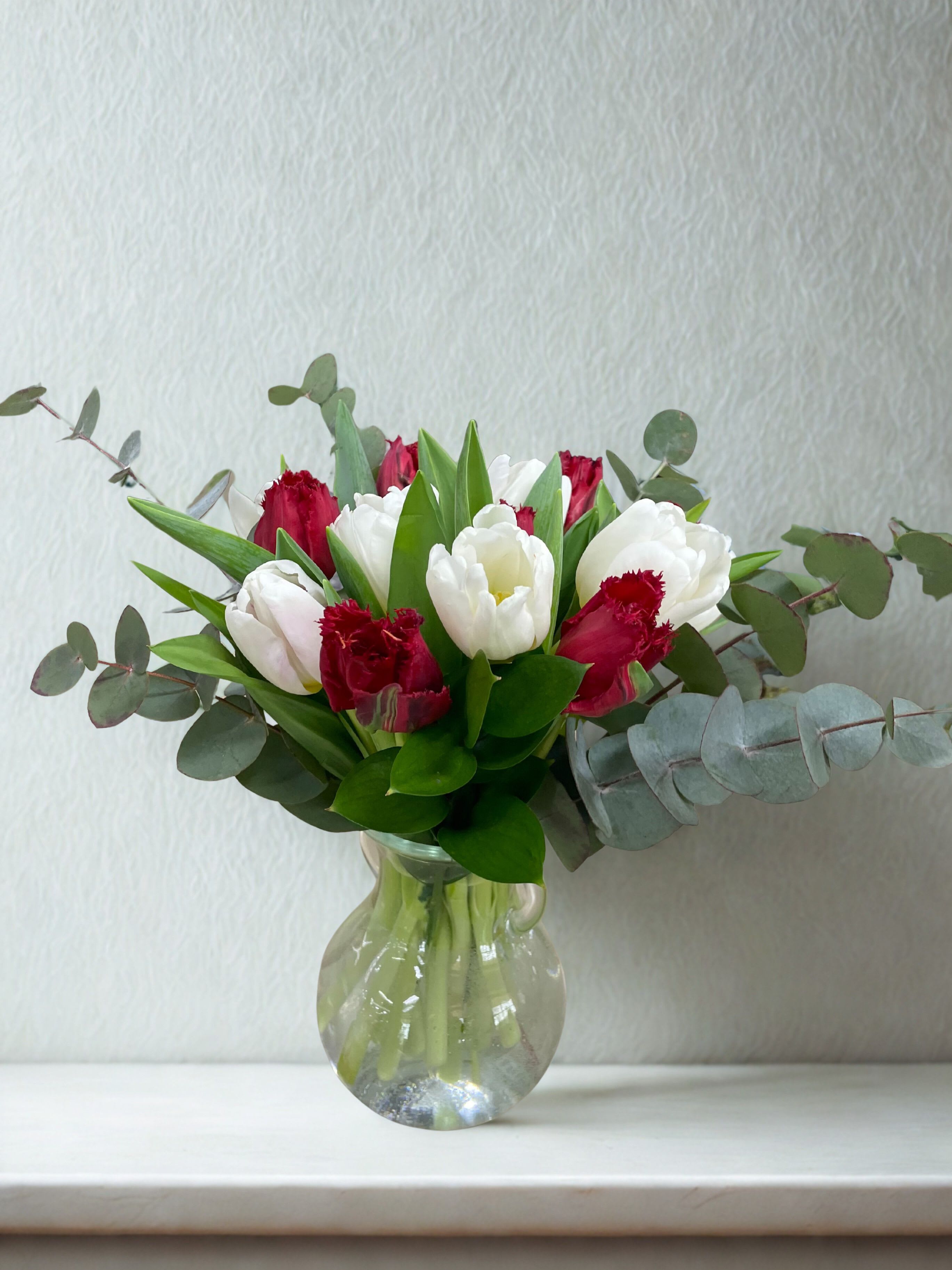 Tulips In Love - The contrast of creamy white and rich red tulips creates a look that’s both romantic and refined, while the eucalyptus adds a fresh, calming scent and a modern, airy feel. It’s fresh, elegant, and timeless