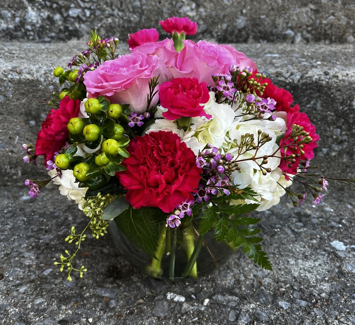 Precious Petals  - This arrangement has roses, hydrangeas, carnations, mini carnations, Hypericum, wax flower and seeded eucalyptus. Made in a small bubble bowl.