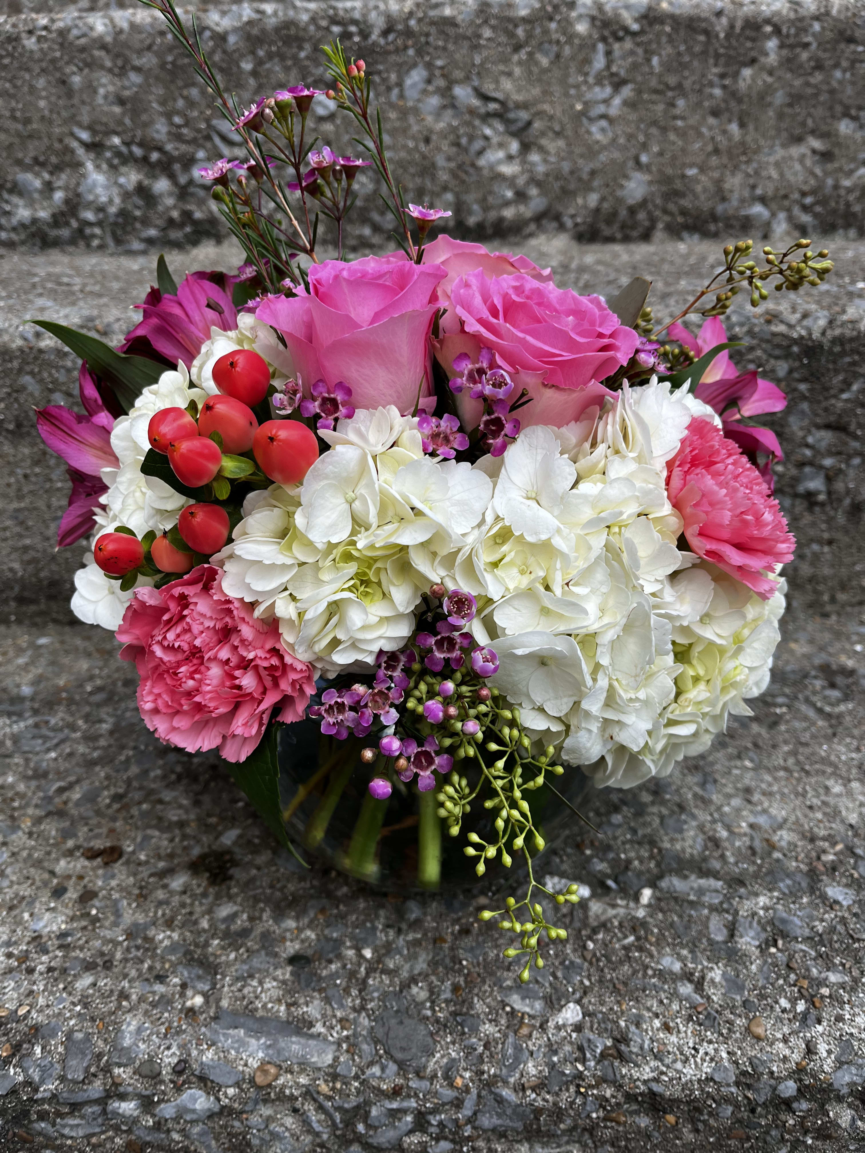 Pretty In Pink - This arrangement has roses, hydrangeas, Hypericum, carnations, alstroemeria, Waxflower, and see if eucalyptus. Made in our small bubble bowl 