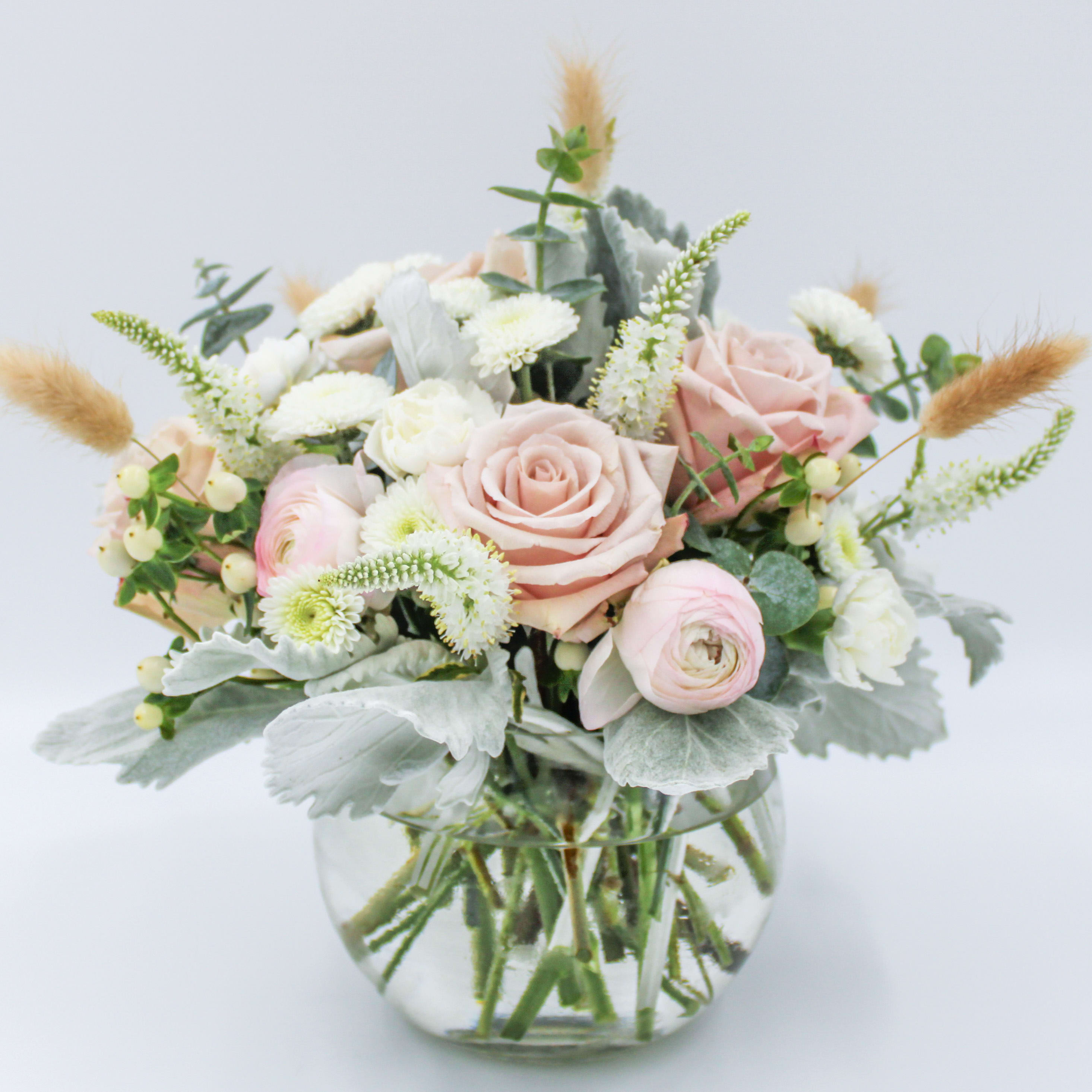 Boho Babe - A Bohemian, neutral toned and calming display of dried Bunny Tails, sand colored Roses, Blush Ranunculus, White Veronica, White Hypericum Berries, White Mini Carnations, White Button Mums, Dusty Miller and Eucalyptus in a six inch Clear Glass Bubble Bowl. 