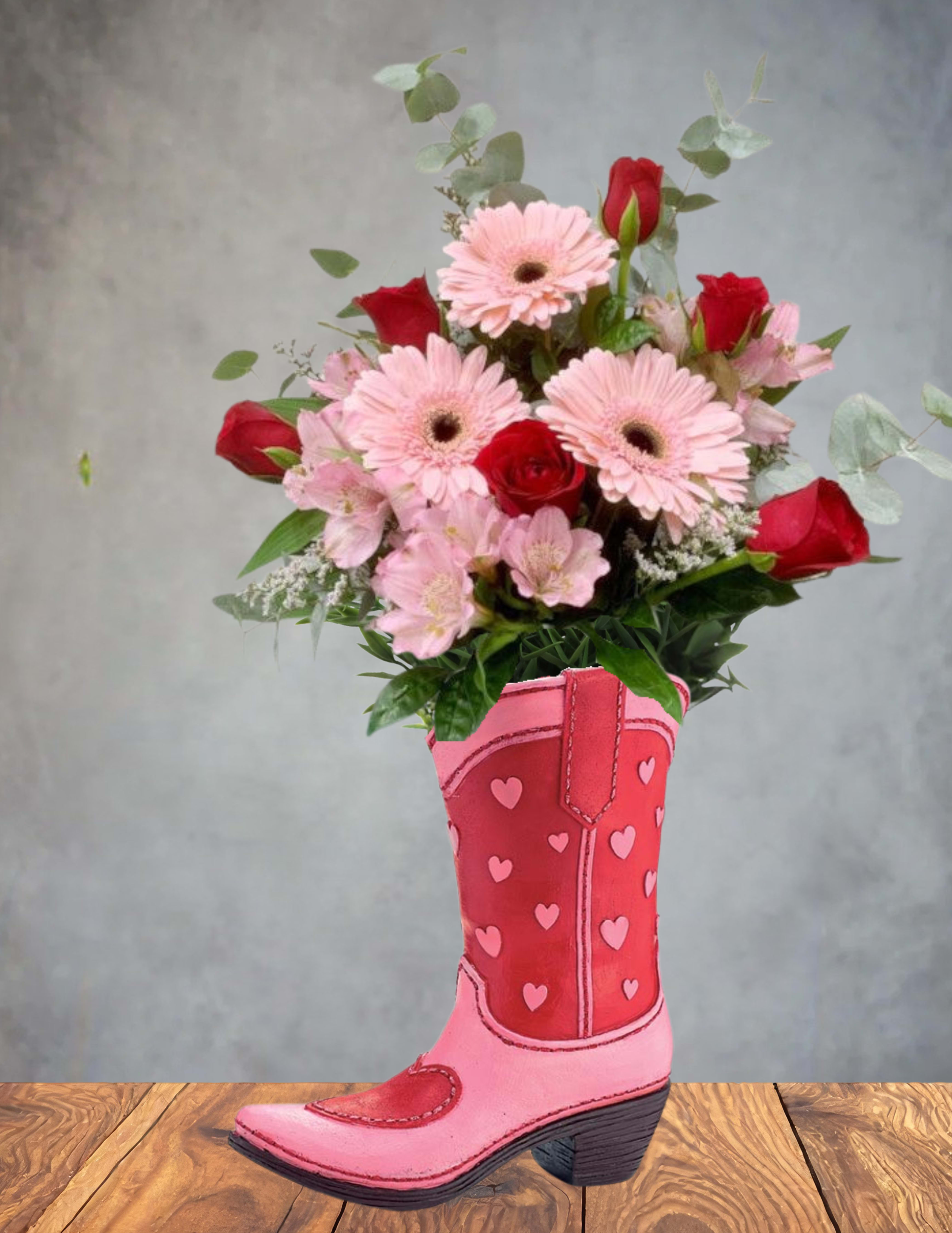 Gerbera Gallop - Gerbera Gallop   A joyful burst of blooms with a cowgirl’s kick. Gerbera Gallop trots in with a pink-and-red heart-speckled boot brimming with bold gerbera daisies, passionate red roses, and playful greenery. It’s a spirited blend of rustic charm and Valentine’s sweetness, perfect for someone who loves their flowers with a little flair.  Whether it’s a gift for your sweetheart or a treat for yourself, this arrangement says “giddy up, gorgeous” in the most romantic way.