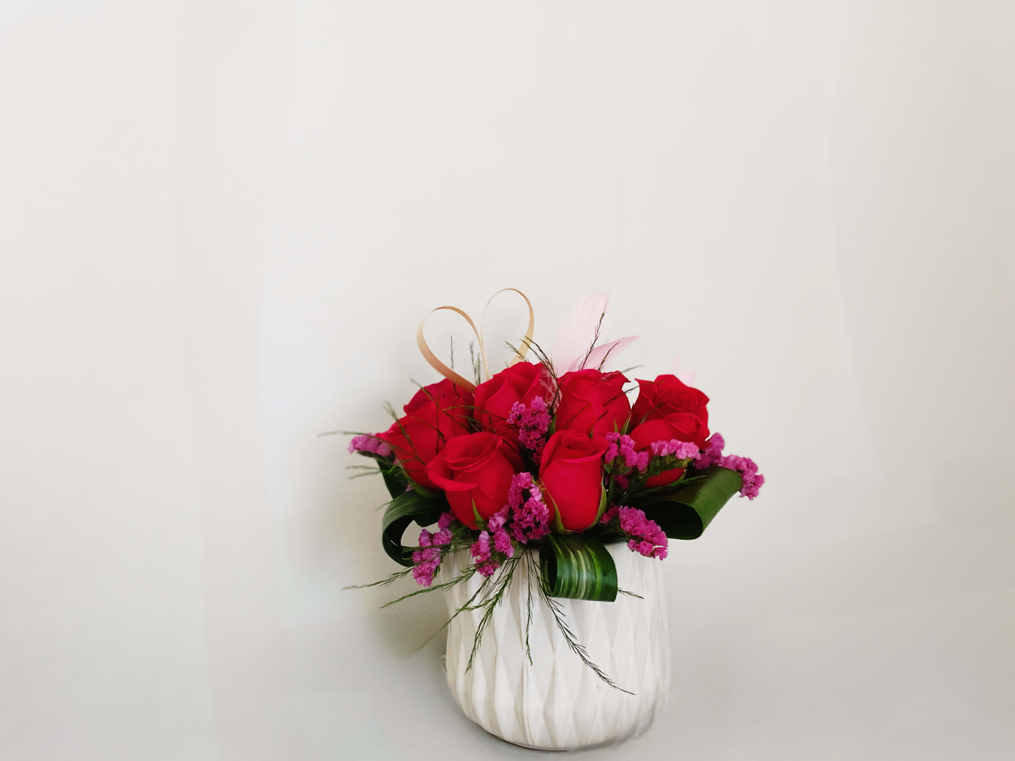 Sweet Tart Rose bouquet  - Modern and romantic  arrangement of a dozen red and hot pink roses cleanly designed and finished off with foilage, pink filler flowers,a bamboo heart with a touch of light pink plumes. Premium would include extra roses and volume in size. For that special valentine that loves a modern luxurious look. 