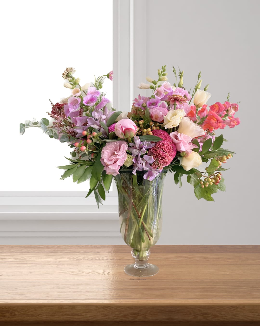 Modern &amp; Grand - A grand and modern asymmetrical floral design in a tall glass fluted vase (or similar) featuring a mix of lush fluffy florals, berries, snapdragons and other premium blooms. Color palette will be warm tones and shades of pink, peach, coral and lavendar