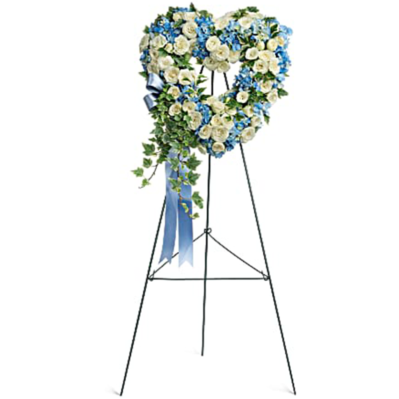 Pure Heart Standing Spray - This beautiful and petite, 16" heart-shaped wreath of sky blue hydrangea and snow white roses is a touching tribute to your love. This heartfelt arrangement features blue hydrangea, white spray roses, and variegated ivy. Delivered on a wire easel.