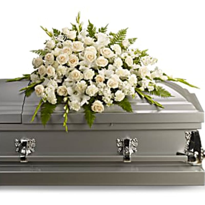 Silken Serenity Half Casket Cover - A gracious and tender tribute to a beautiful and cherished life, this elegant half casket spray radiates loveliness and serenity. Its soft and heavenly white flowers delicately speak your heartfelt emotions. Lovely flowers such as crème roses, white gladioli, stock and carnations, gracefully arranged with sword fern and other greens.
