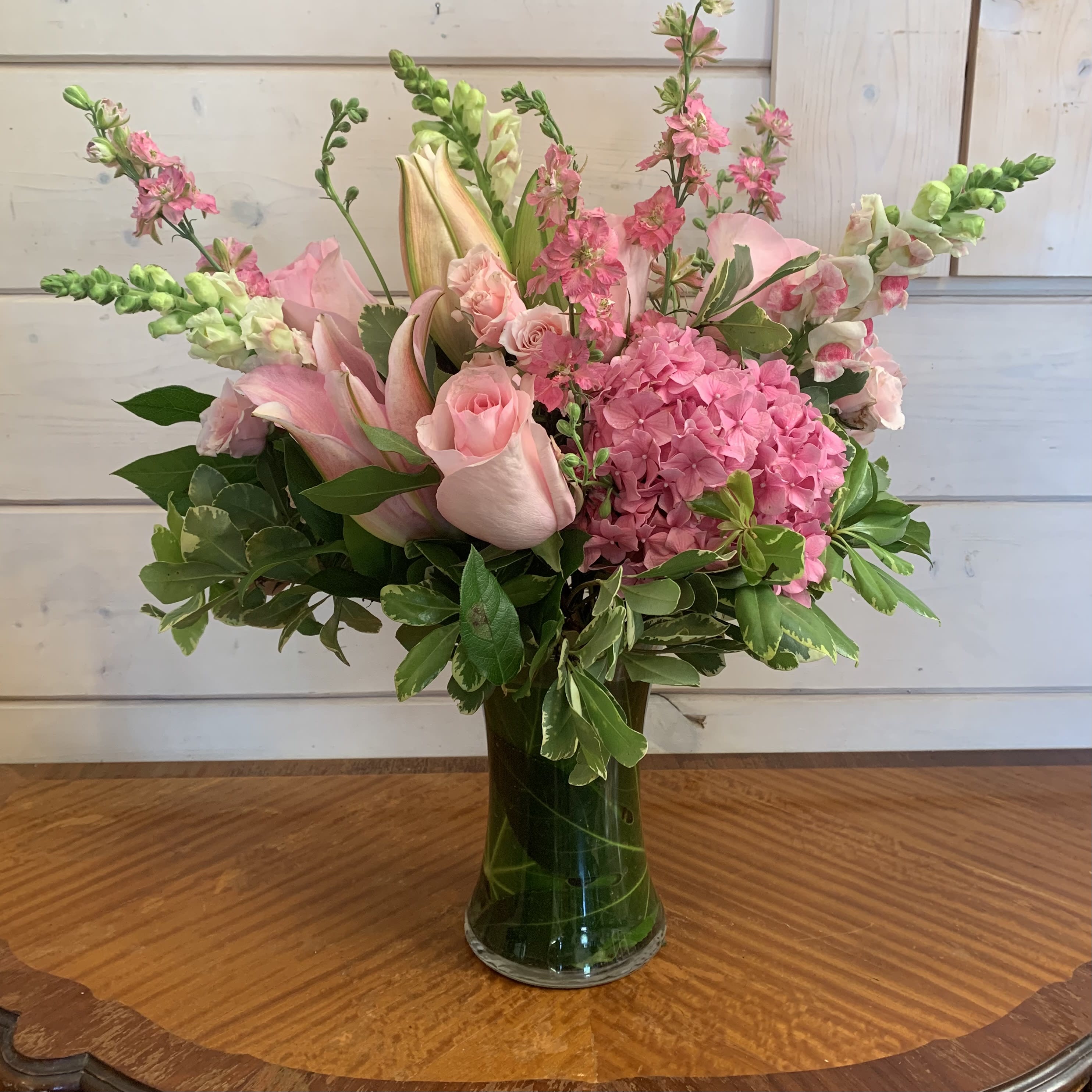 The Wishes &amp; Blessings Bouquet - The Wishes &amp; Blessings Bouquet is a stunning way to offer your condolences for their loss and commemorate the life of the deceased. Soft pink roses spray roses Oriental lilies hydrangea and larkspur are brought together in a leaf lined glass vase to create an eye-catching display of soft serenity.
