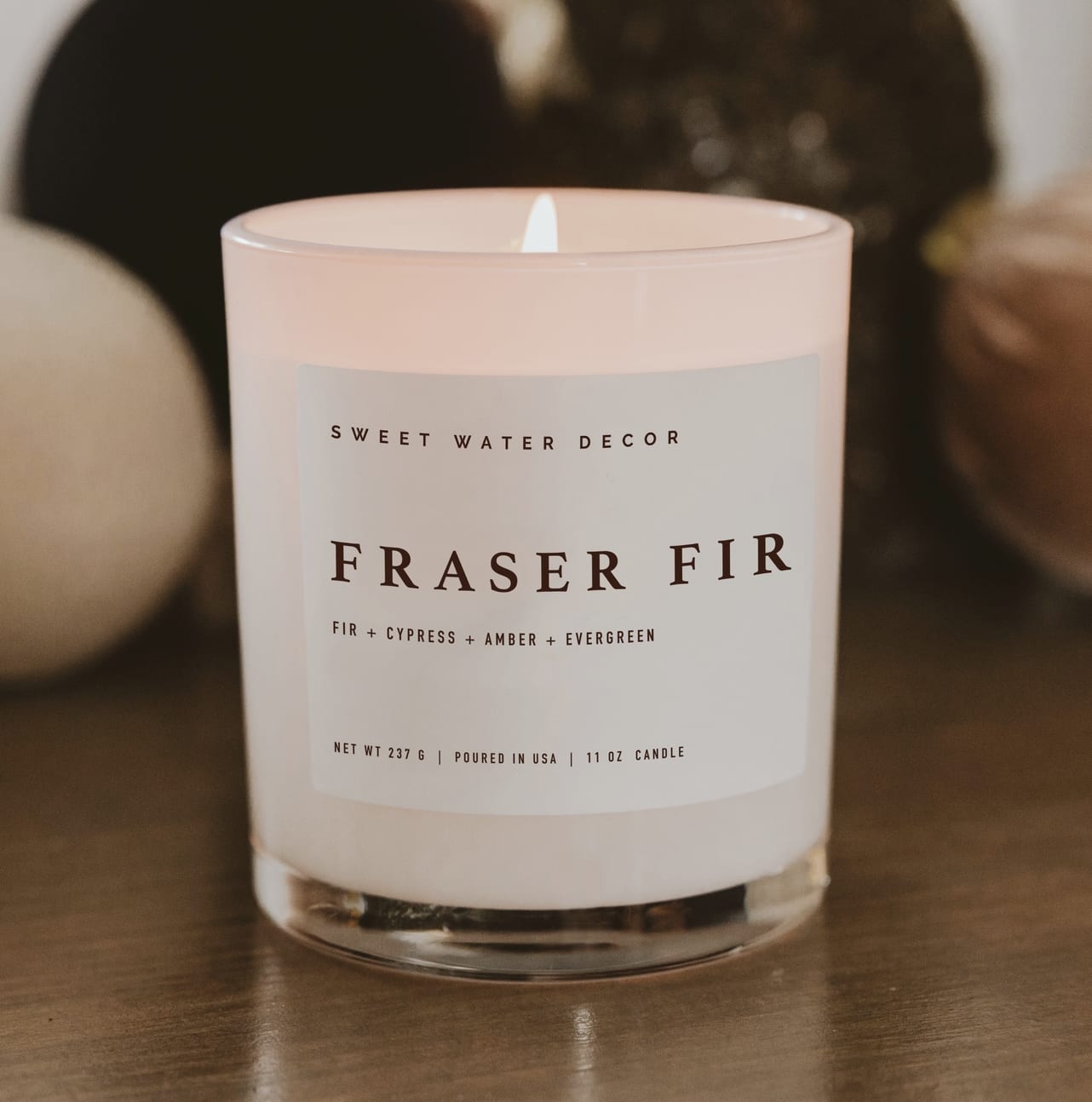 Fraser Fir 11 oz Soy Candle - Our Fraser Fir fragrance perfectly captures the crisp scent of a Christmas tree and brings the outdoors inside. A classic Christmas favorite in an elegant white glass jar, whose simple design blends seamlessly with any Christmas decor. A timeless addition to holiday candle collections and seasonal displays.