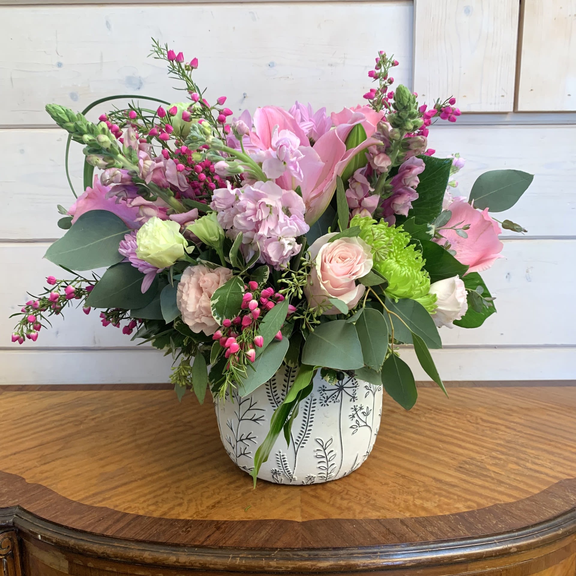 Secret Garden Bouquet - Assorted pink roses and dancer lilies with pink lisianthus, green and lavender chrysanthemums, and pink stock arranged in a black and white embossed pot with seasonal filler flower. Approximately 14" tall and 12" wide.