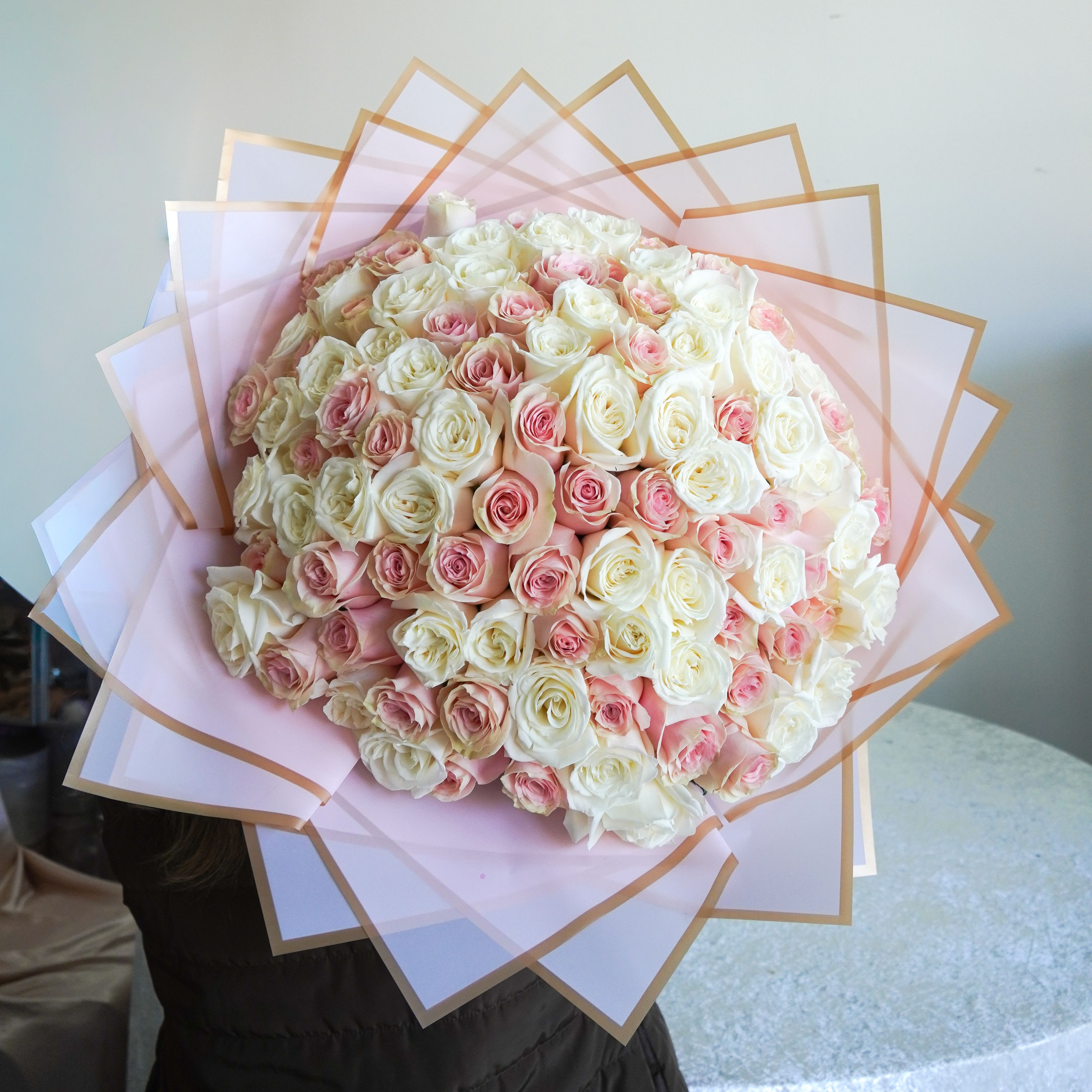 Pink and White Roses Wrapped Bouquet - A luxurious bouquet of fresh blush pink and white roses, beautifully wrapped in soft pink paper with elegant gold detailing. Perfect for anniversaries, celebrations, or just because.   [Image Shown is 100 Roses example]