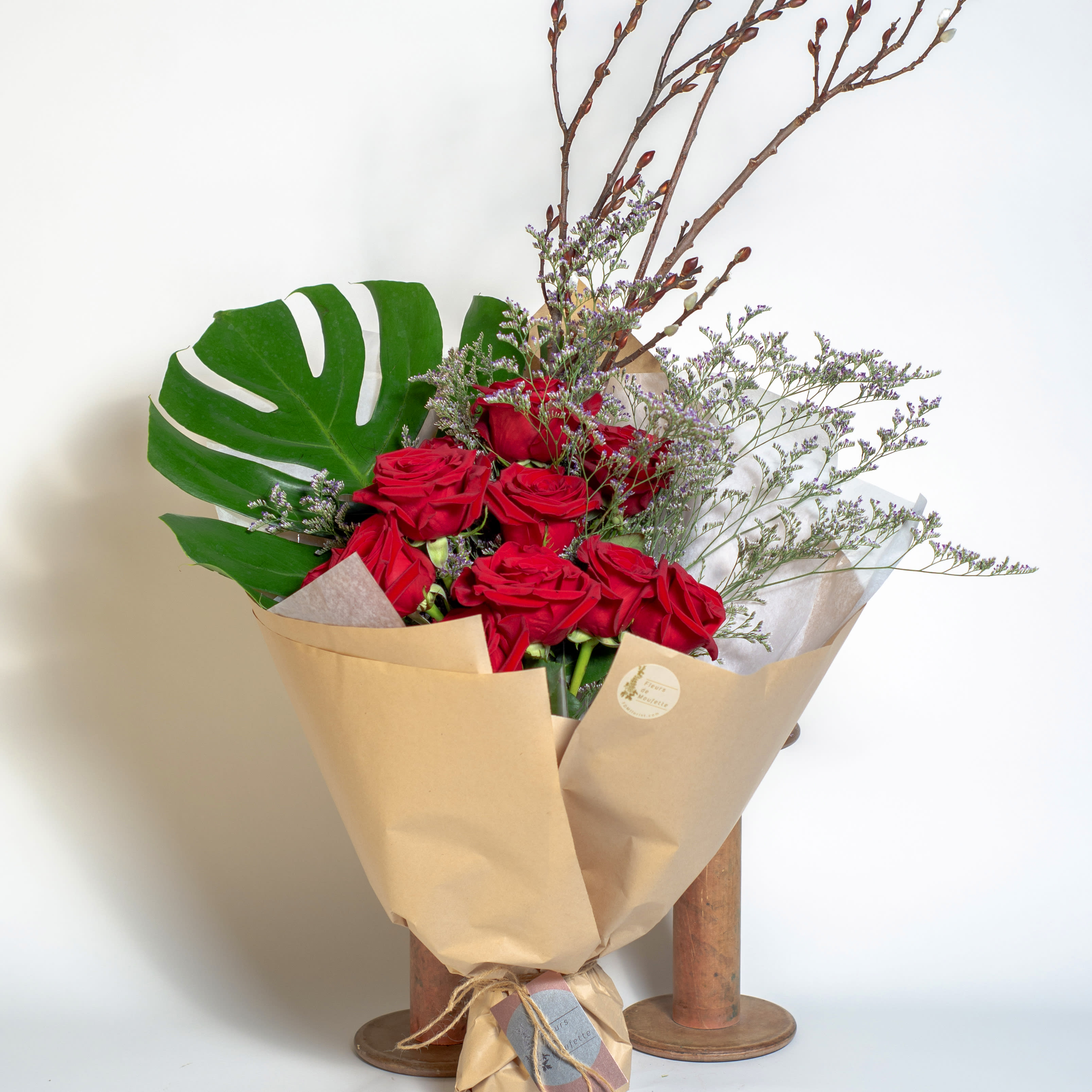 Cecile (wrapped bouquet) - A dozen of red roses are wrapped in paper, dressed up with a monstera leaf and pussy willow twigs. Express your love with red roses bouquet in a unique style.