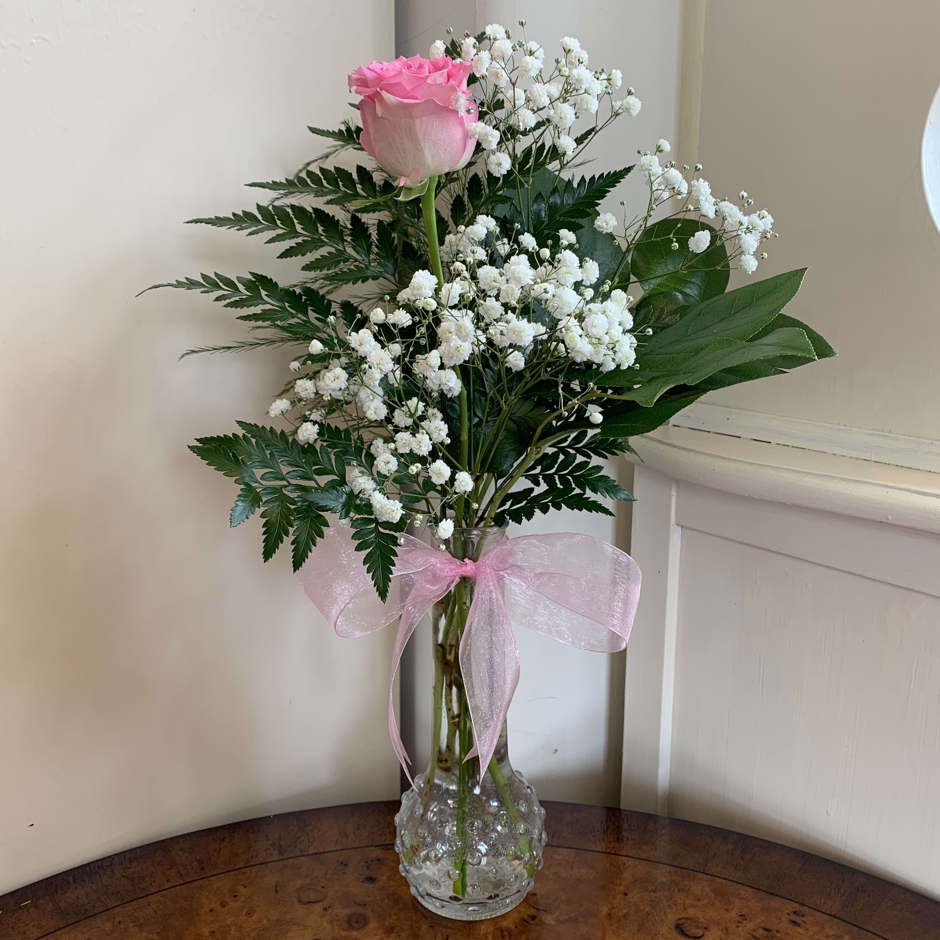 Pale Pink Sweetheart Bud Vase - one long stem pale pink rose, baby's breath and greens in a pink bud vase. Pale pink organza bow