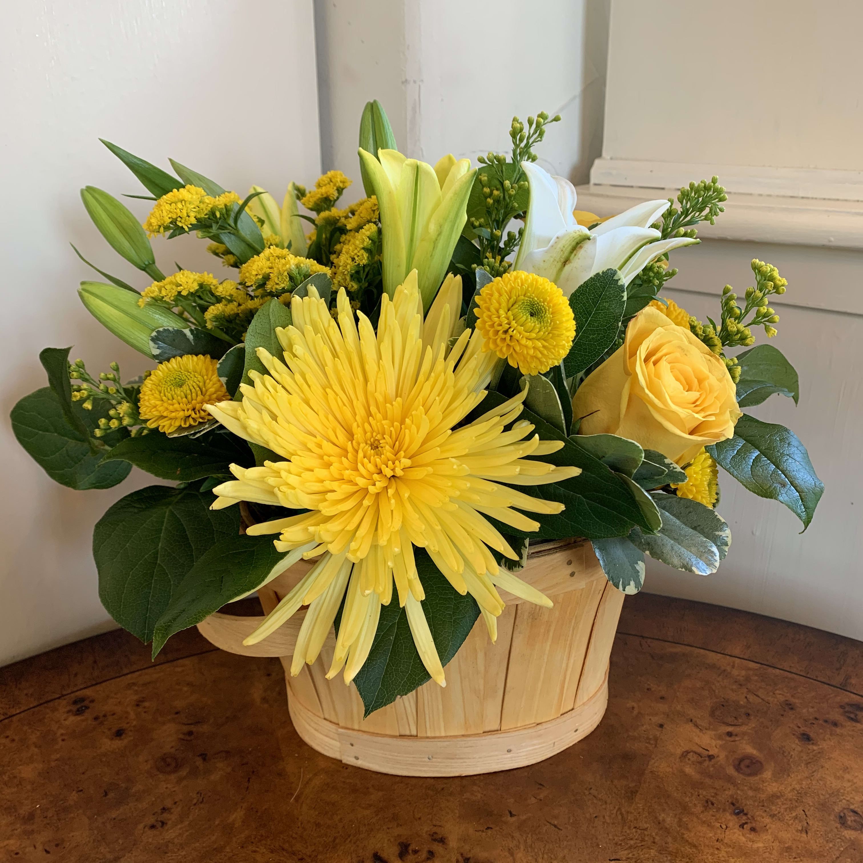 The Uplifting Moments Basket - Arranged just for you to send to your recipient to boost their mood, celebrate a moment, or to simply say hello this sunlit flower bouquet is an unforgettable gift. Yellow roses, button poms, and solidago shed light on any situation mingling with white Asiatic Lilies and lush greens arranged beautifully in a oval woodchip basket to give it a natural backdrop in which to truly shine. A wonderful thank you, get well, or thinking of you gift! GOOD bouquet includes 9 stems. Approx. 9"H x 10"W. BETTER bouquet includes 12 stems. Approx. 10"H x 11"W. BEST bouquet includes 16 stems. Approx. 11"H x 12"W.  Please be advised this arrangement is made in foam and so it could only last 4-5 days with daily watering. 