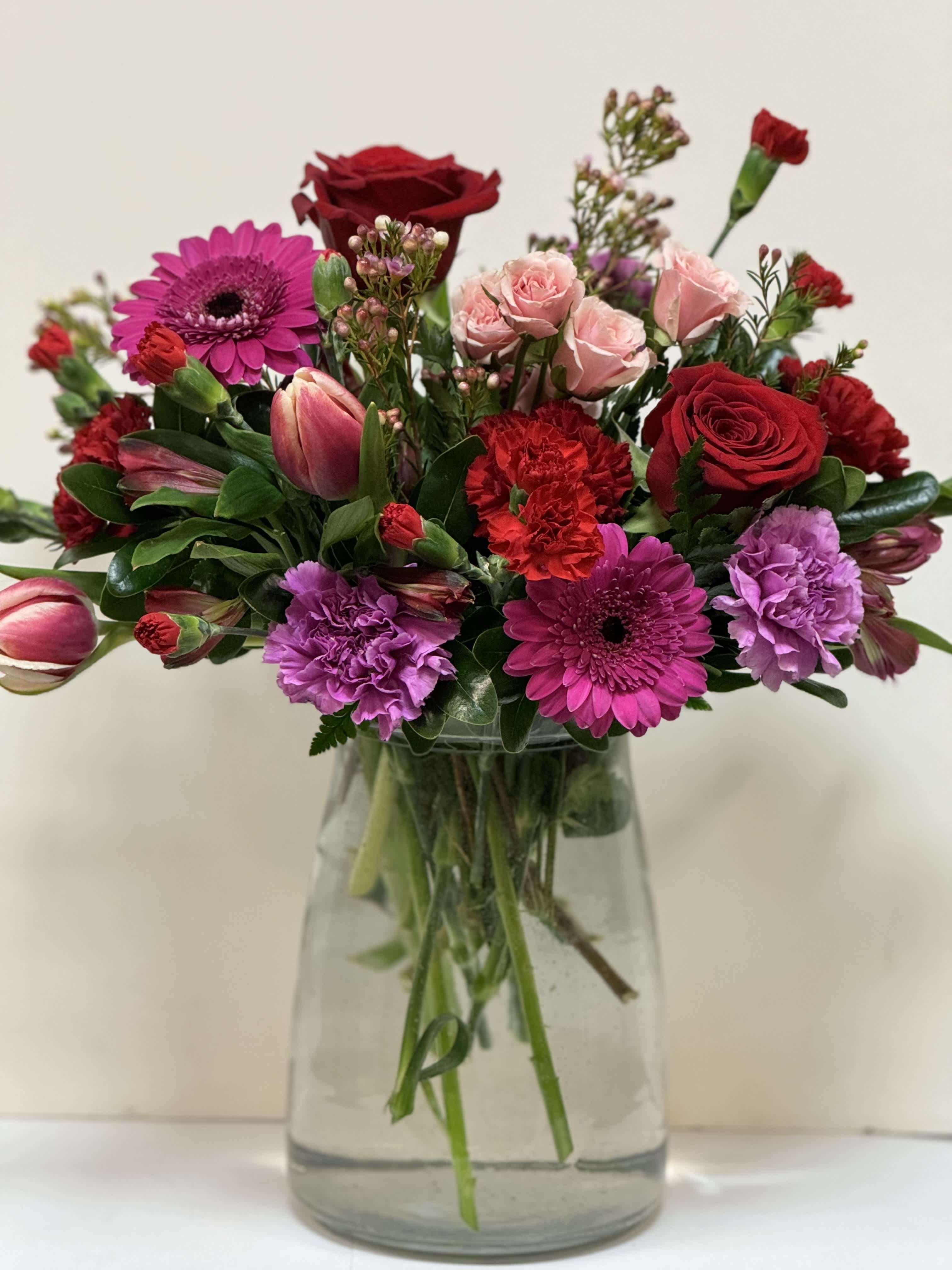 Hot Stuff Valentine - Bright reds and shades of pinks , mixed seasonal florals in a clear glass vases