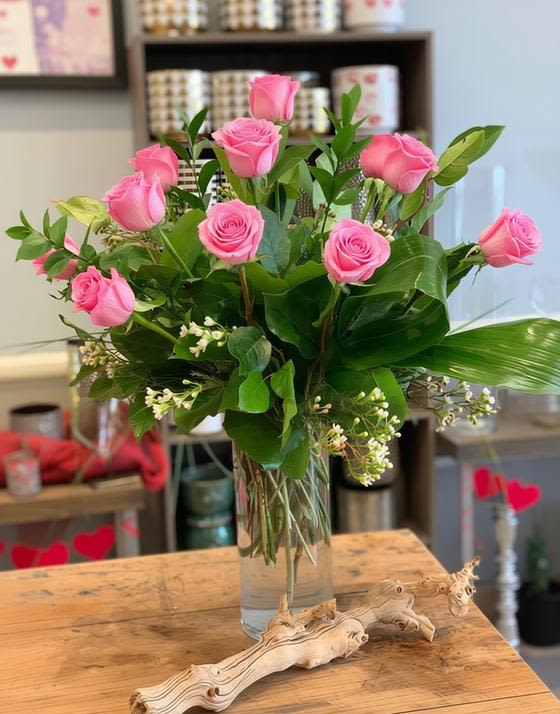 Dozen Pink Roses - A timeless expression of love and beauty, this arrangement features a dozen pink roses, complemented by delicate wax flowers for added charm.  Standard – Dozen pink Roses with Wax Flower Deluxe – Eighteen pink Roses 