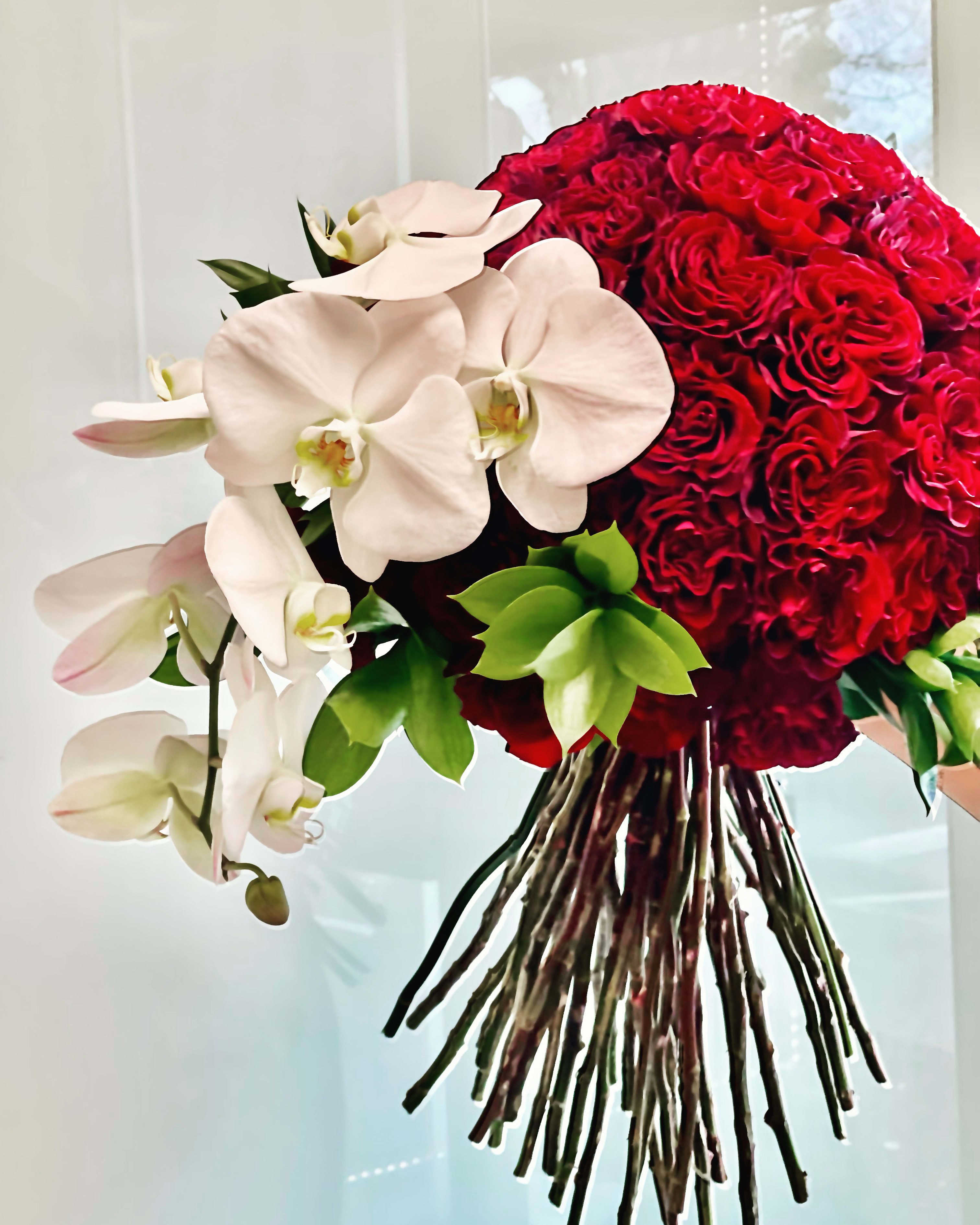 L'amour Sculpte"  - L'amour Sculpte is a refined elegance statement of passion and elegance .Lush red velvet roses are  artfully gathered into romantic ,dramatic ,rounded silhouette ,paired  with cascading white orchids for a striking contrast of color ,texture and form .This arrangement balance romance and sophistication . Perfect for grand romantic gestures ,anniversary ,celebration of love , or elevate interior .