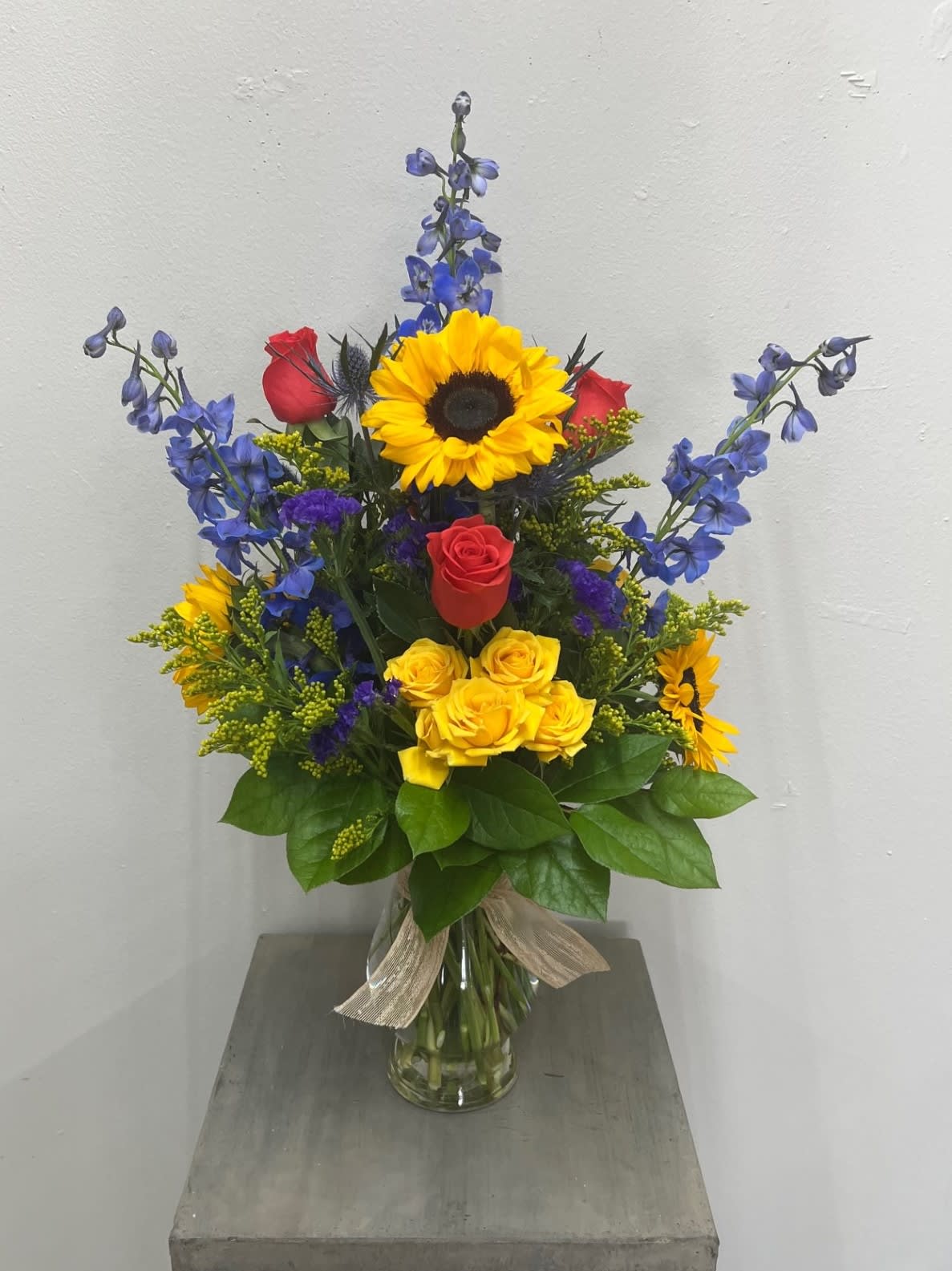 Feels Like Summer - Beautiful bright summer colors to get you going! Plus, a super cute container ;) Sunflowers, roses, spray roses, blue delph., buttons and more. Flowers and colors may vary depending on availability.   FCF-064