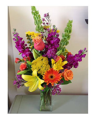 Cheery Sights - Gerber daisies, roses, spray roses, asiatic lilies, daisies, bells of Ireland, wax flowers, snap dragons and yarrow arranged in a tall vase.  All flowers and colors are subject to change due to availability.   FCF-511