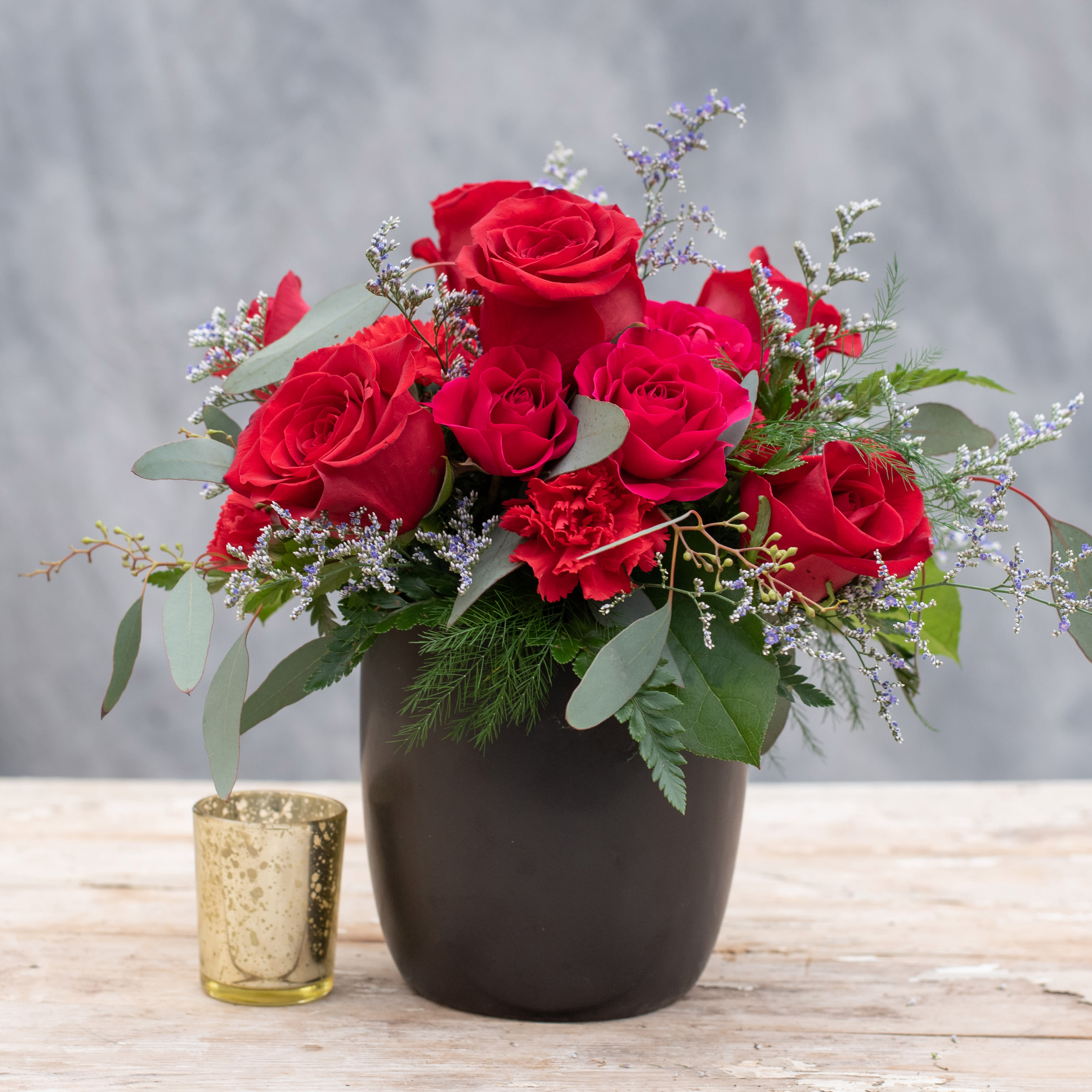 Ruby - Here's a gem, in a modern 5" ceramic cylinder filled with ruby roses, carnations, spray roses and accented with limonium.