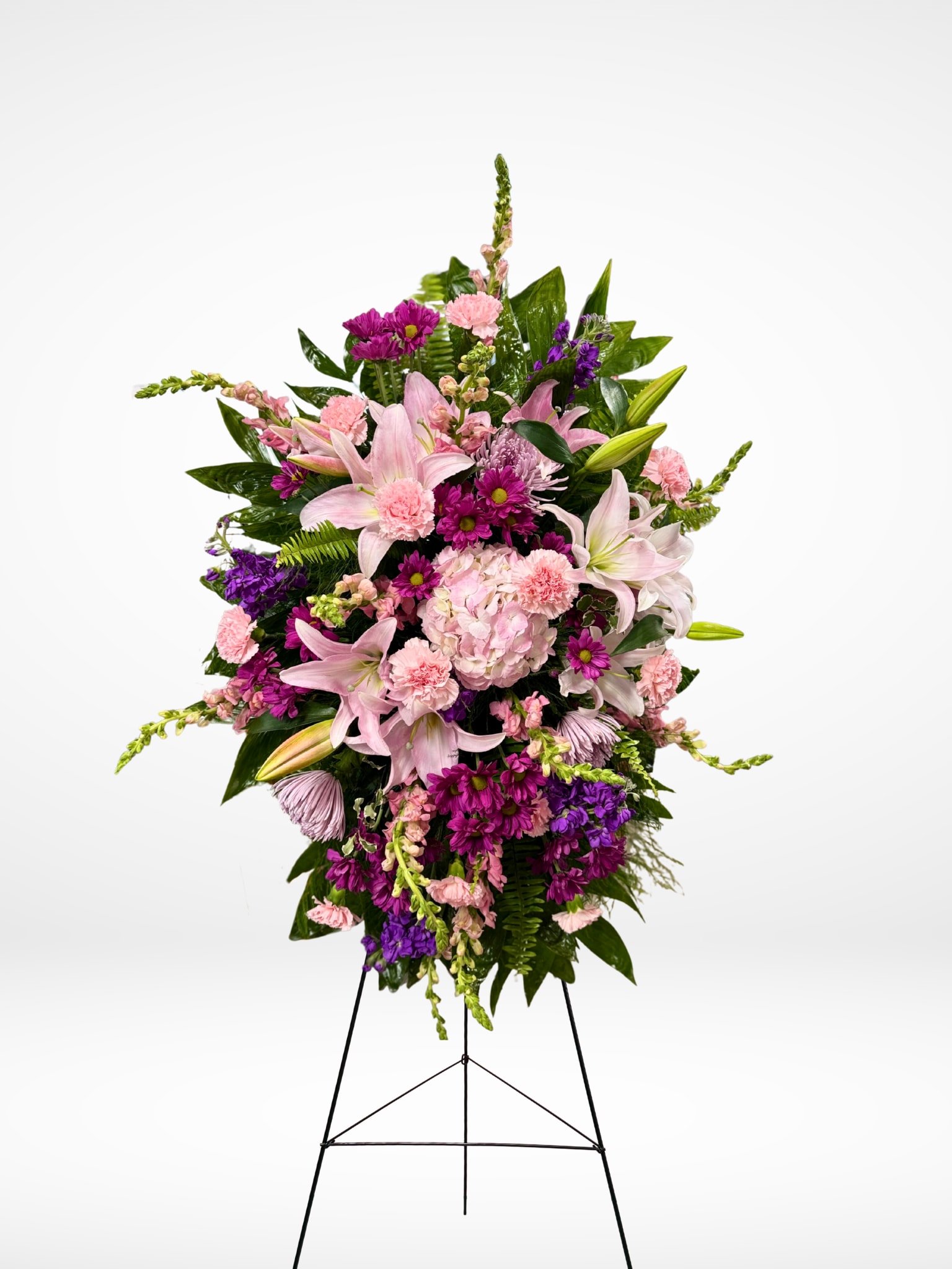 Our Forever Bloom - A Beautiful Tribute to a Life Well-Lived This breathtaking spray of pink blooms is a radiant tribute to a beautiful life. It's a truly reflective celebration of her beauty and the love she shared. This glorious arrangement features:  * Pink hydrangea  * Purple daisies  * Pink oriental lilies  * Pink carnations  * Pink spider mums  * Pink snapdragons  * Purple stock   * Sword fern, asparagus plumosus, and other assorted greenery A Celebration of Beauty and Love 