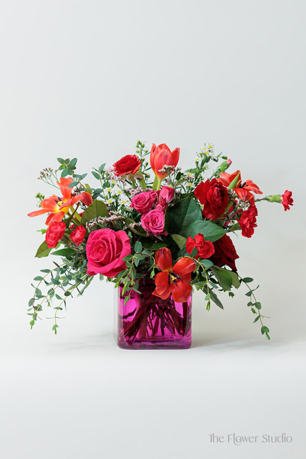Michele - Michele is a pink clear cube vase - full of red roses, tulips, hydrangea, spray roses and accents of greenery.  Perfect for Valentine's Day!! LIMITED QUANTITIES. Measurements are about 16 inches h x 18 inches W. 